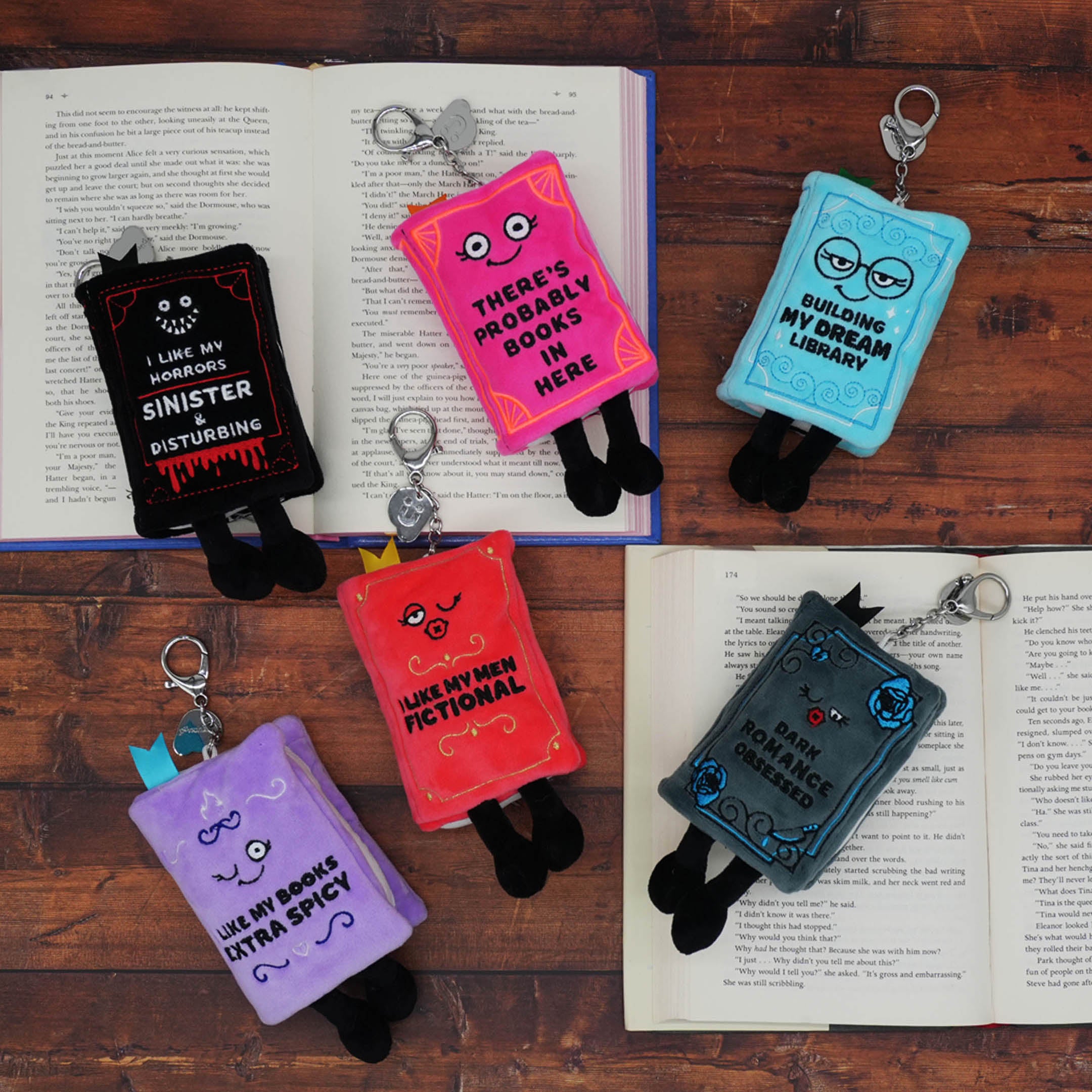 Colorful book-shaped keychains with text on a wooden surface with open books.