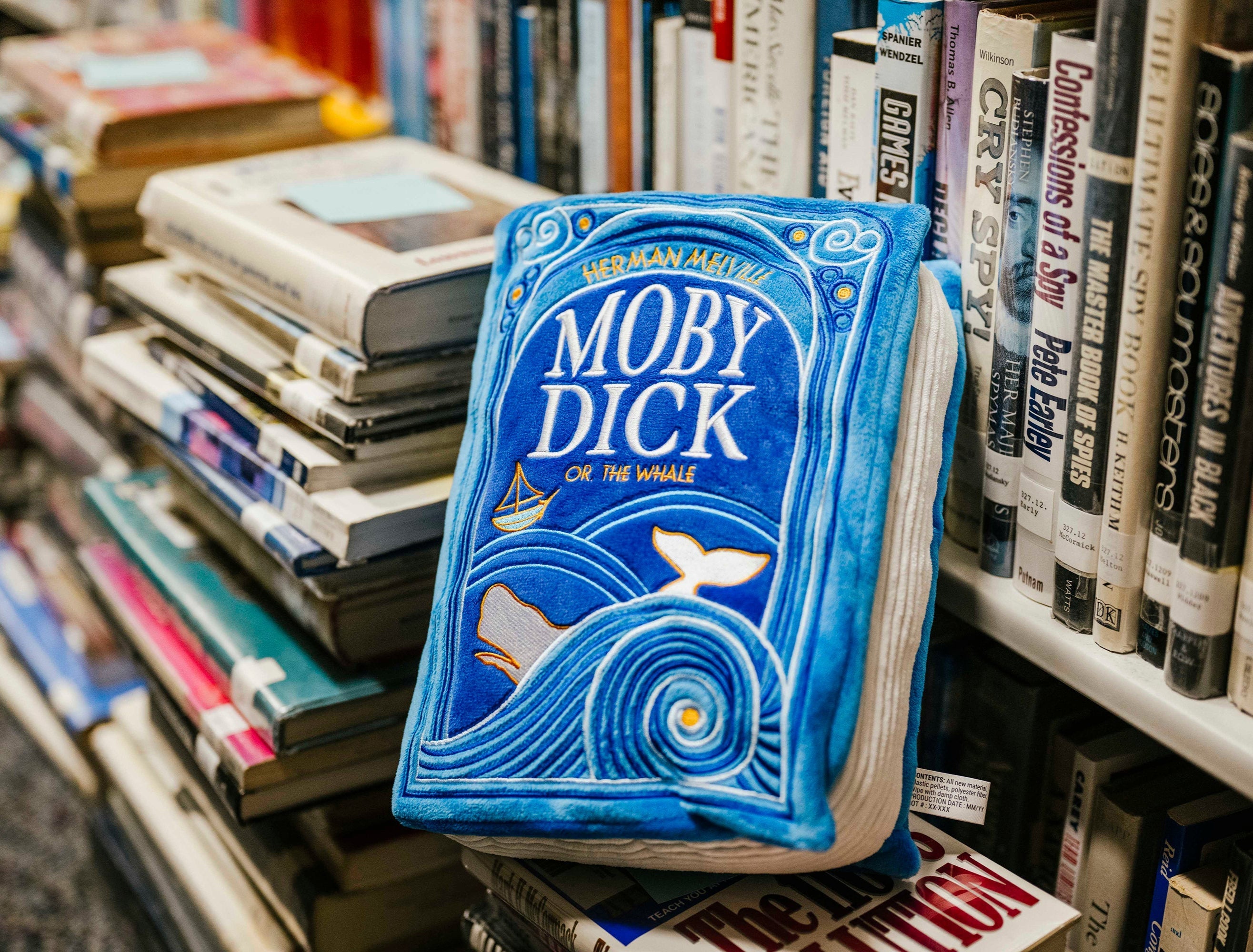 The Moby Dick book plush on a stack of books at the library