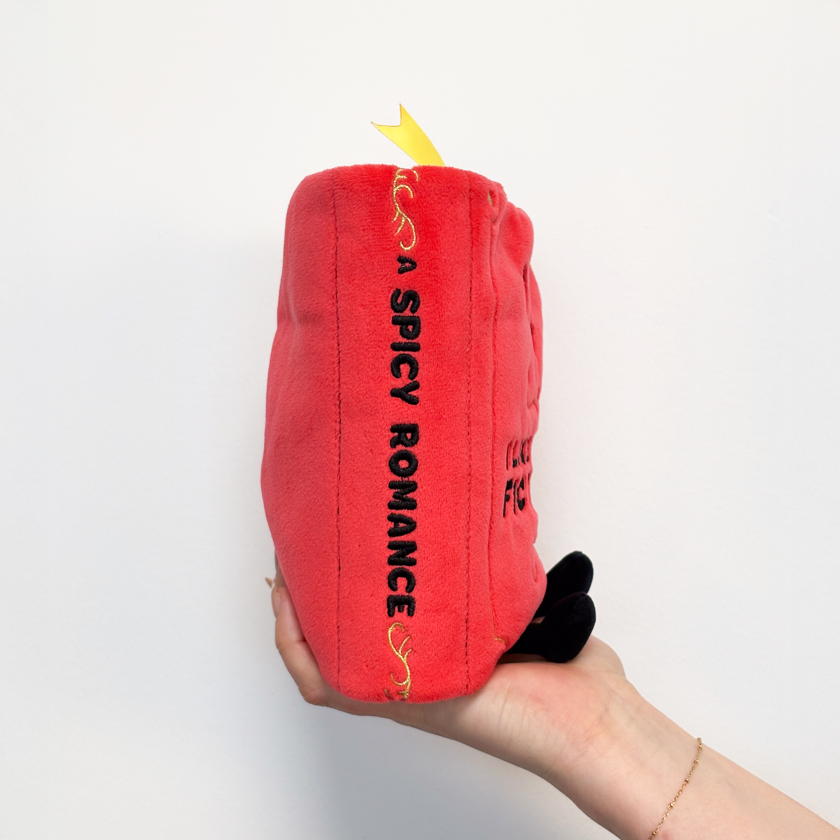 A book plush with 'A spicy romance' written on the spine.