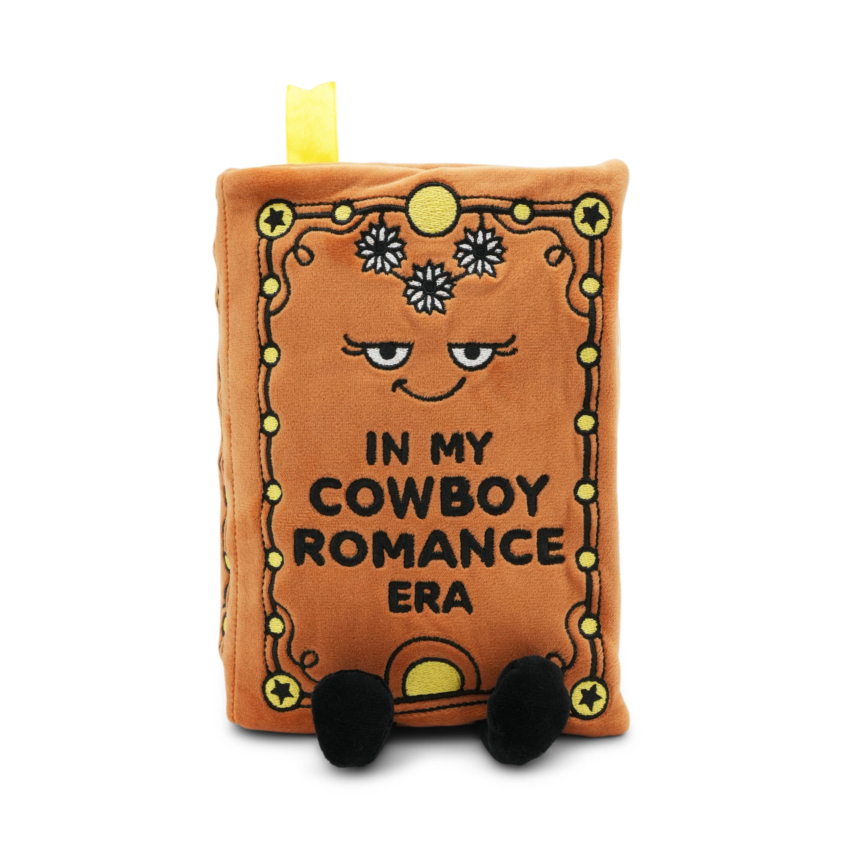 Plushie resembling a book with a face and text 'In my cowboy romance era' on a white background
