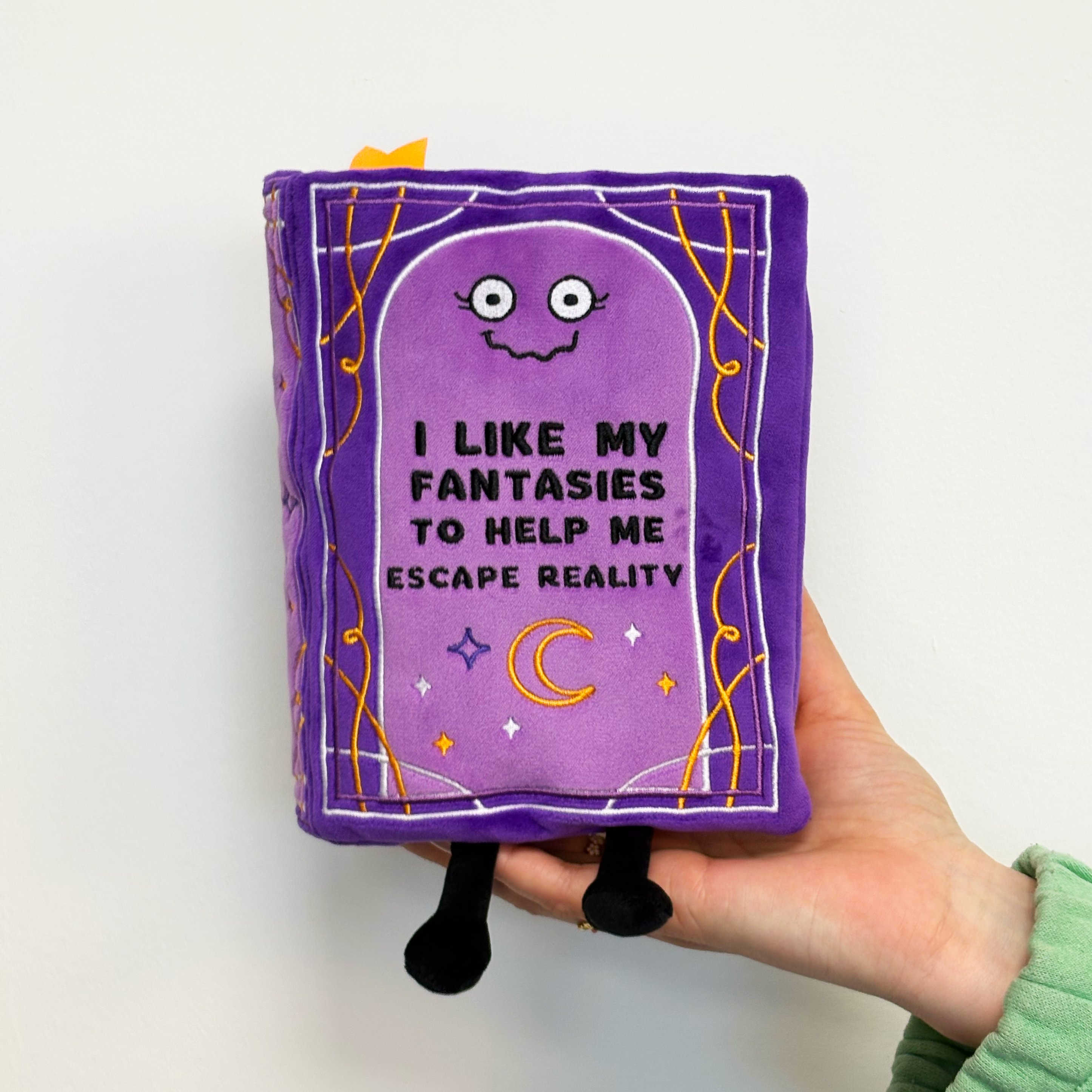 Hand holding fantasy-themed book plush