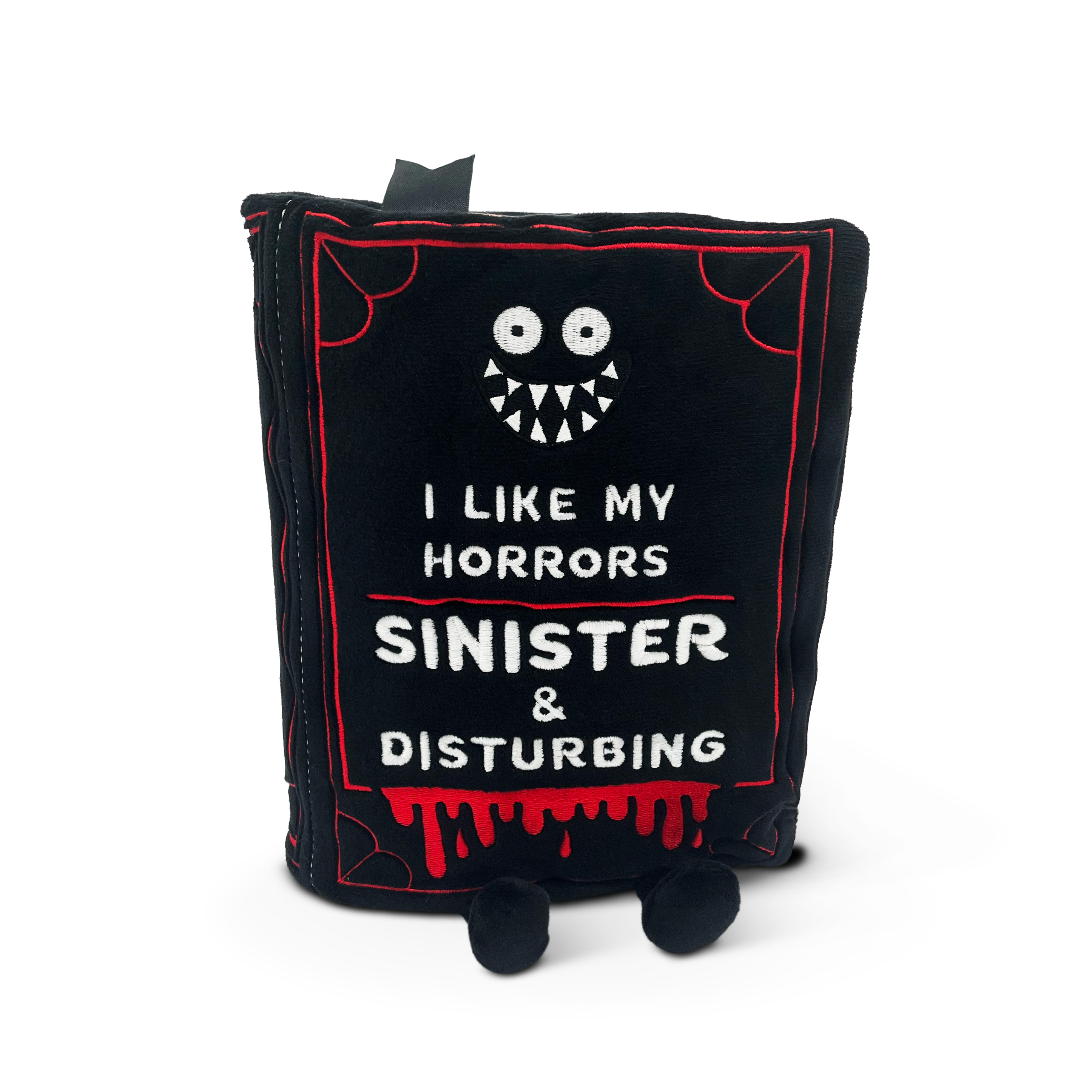 A plush book with a black cover and red accents, featuring the text 'I LIKE MY HORRORS SINISTER & DISTURBING' on the front. The toy has a spooky design with a simulated blood drip and a character with a black outfit and white face.