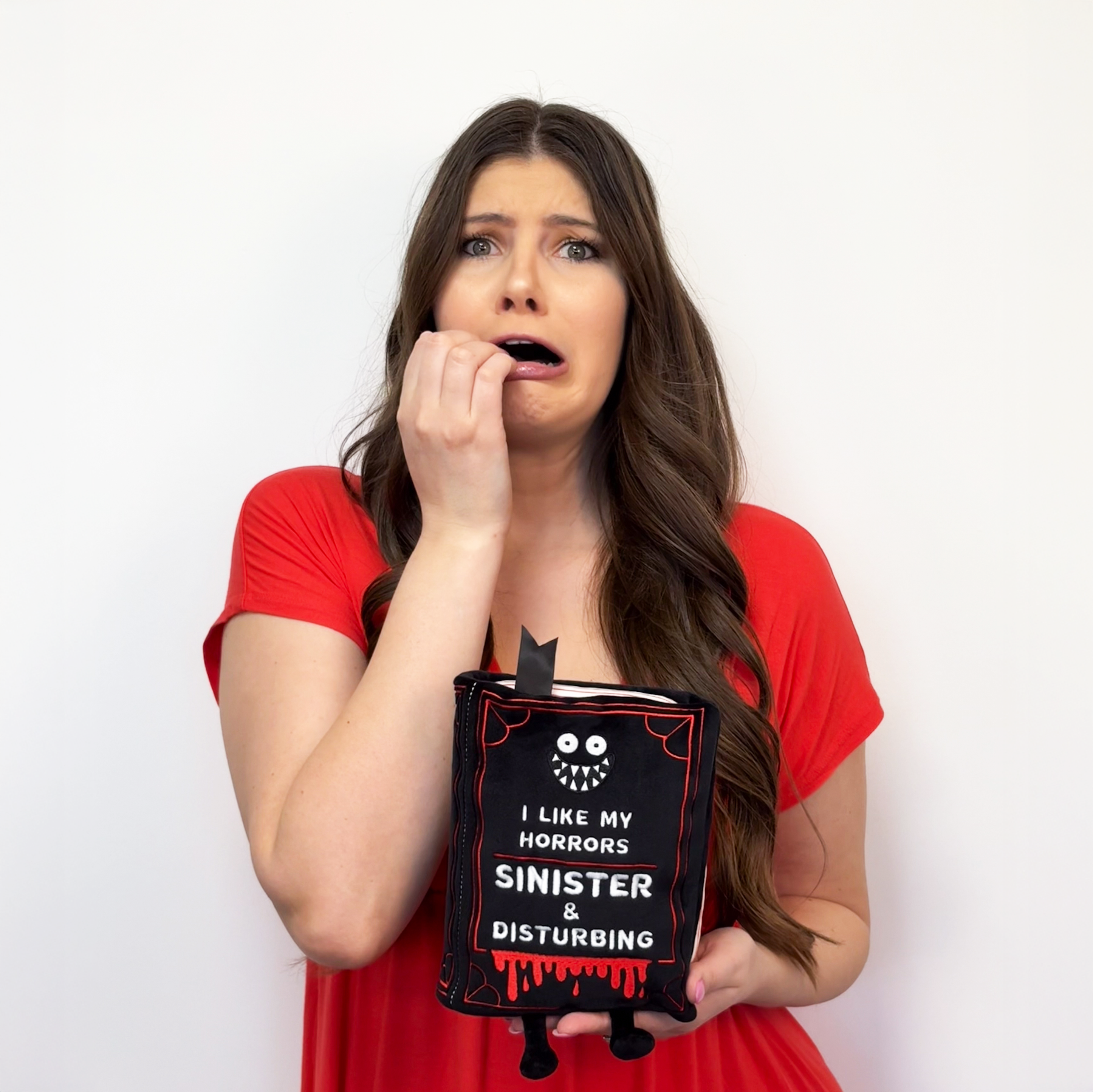 Scared woman holding a horror book plush.