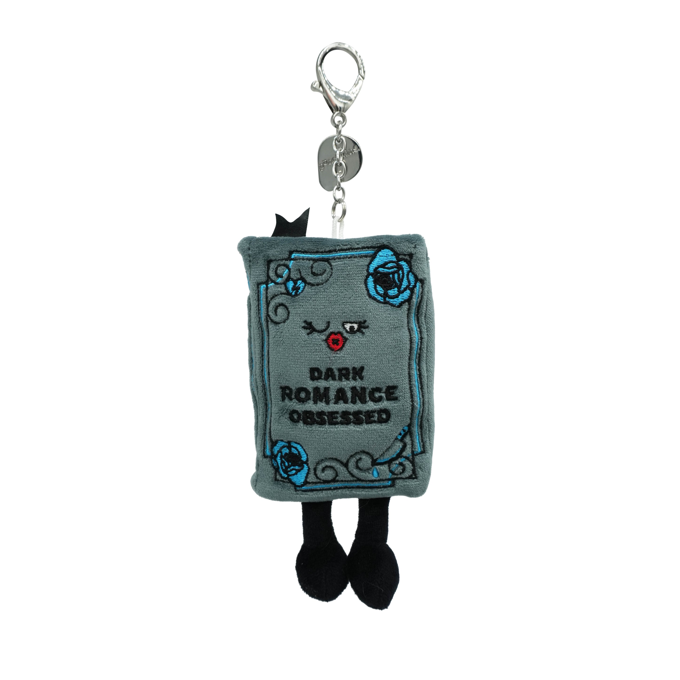 Plush bag charm shaped like a book titled 'Dark Romance Obsessed' on a white background