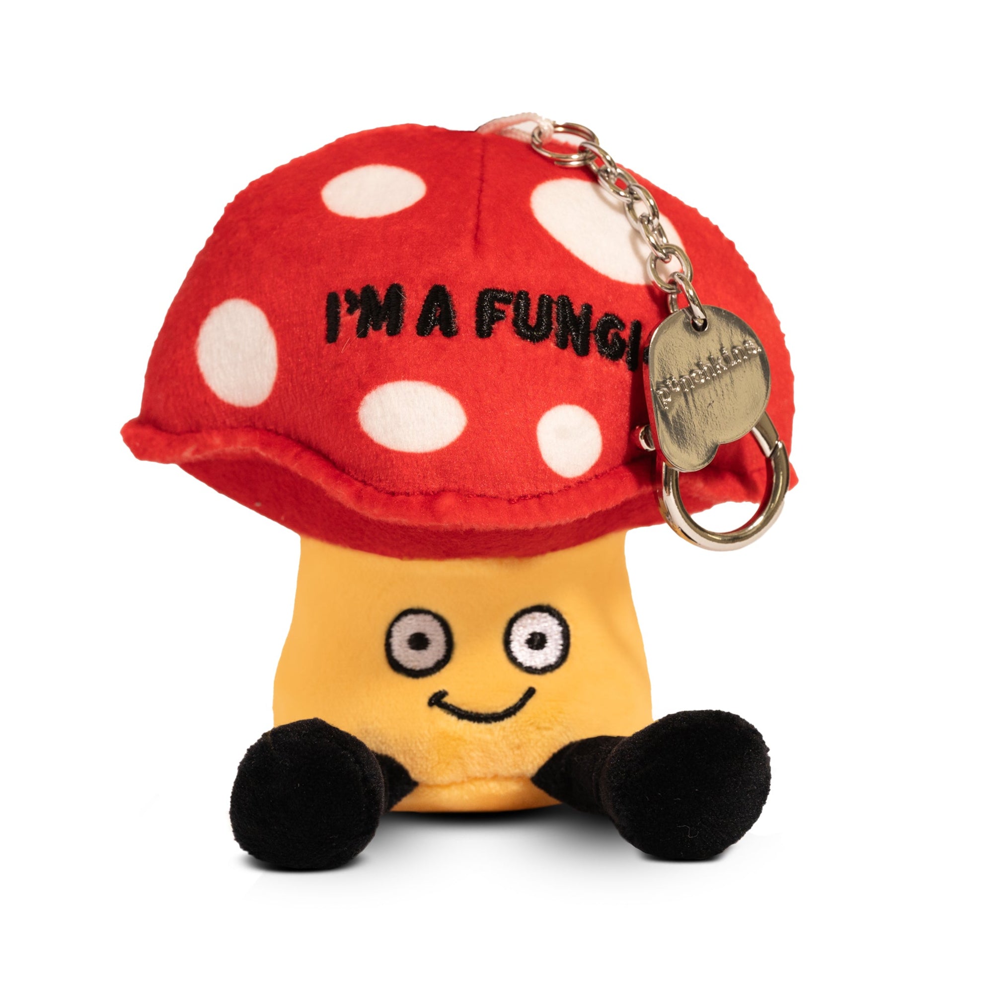 A plush shaped like a red and yellow mushroom with white spots, featuring a playful face, dangly legs, and a red hat with the text 'I'M A FUNGUS'. It is attached to a keyring.