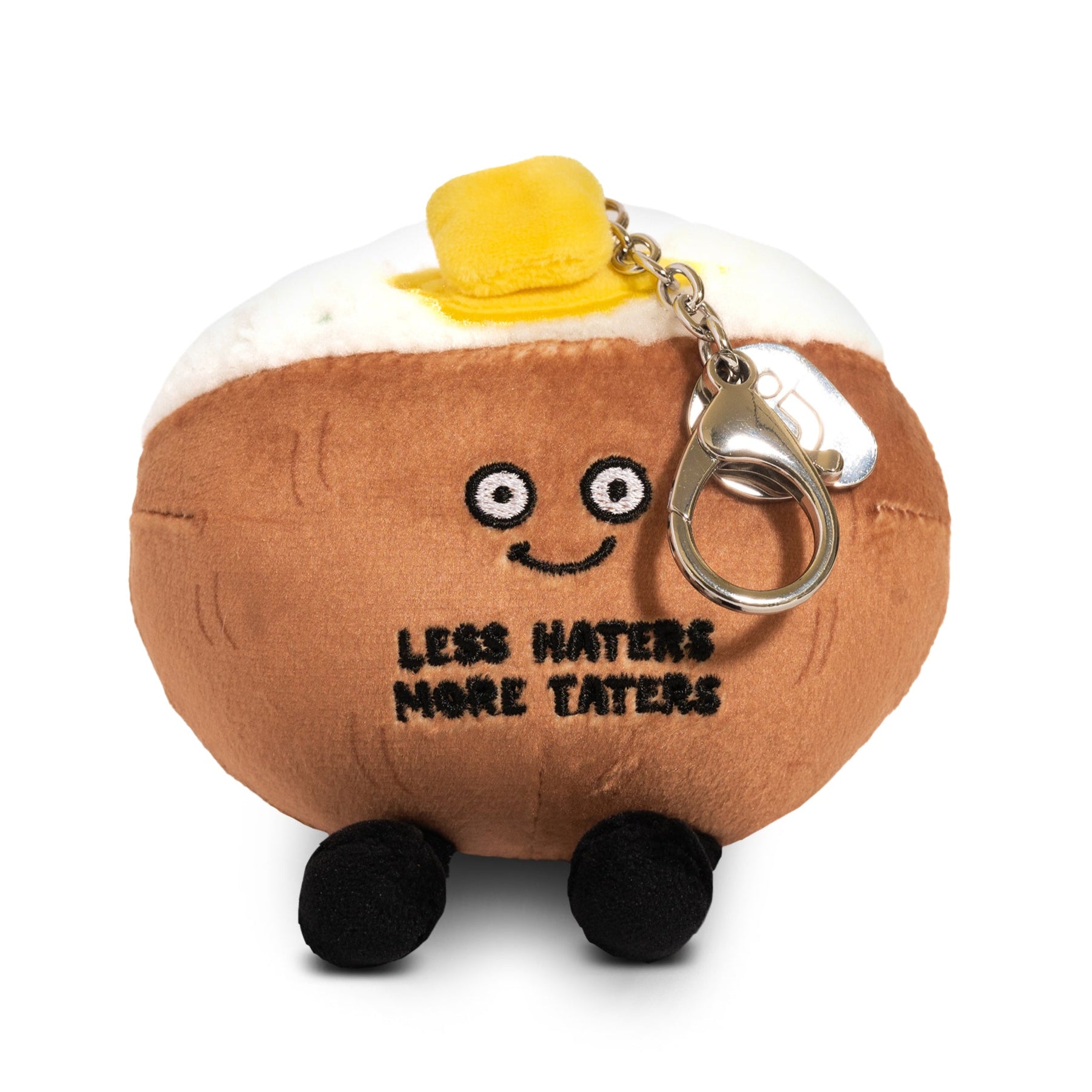 A plush bag charm designed to look like a baked potato with a face and a slab of 3D butter on top. It has the text 'LESS HATERS MORE TATERS' printed on it.