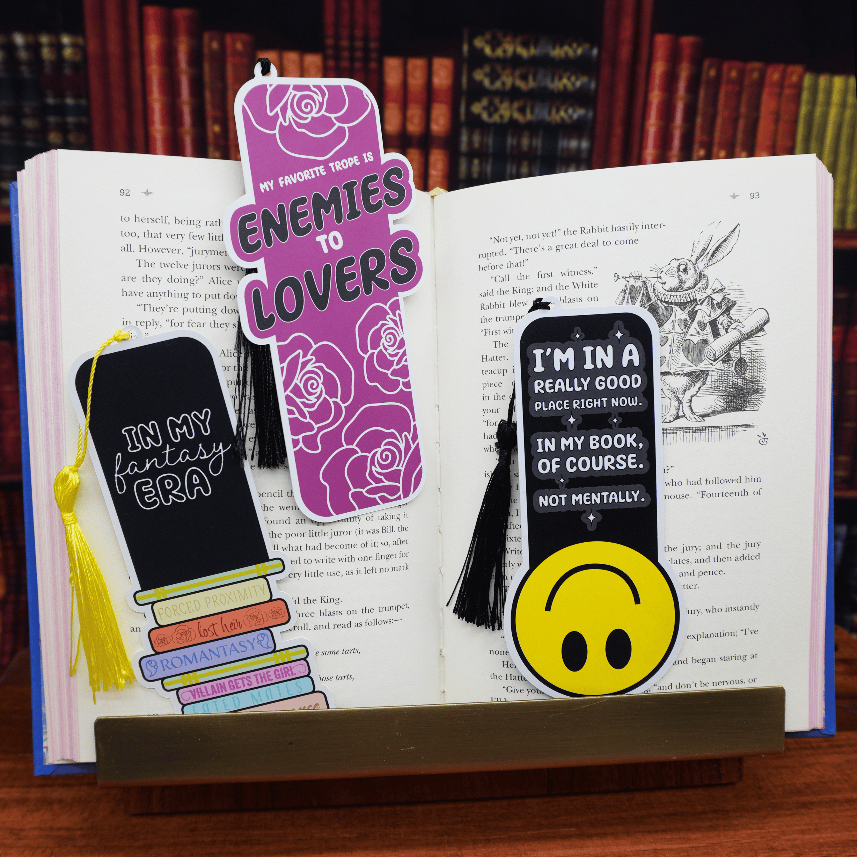 Three unique bookmarks on an open book with a bookshelf background