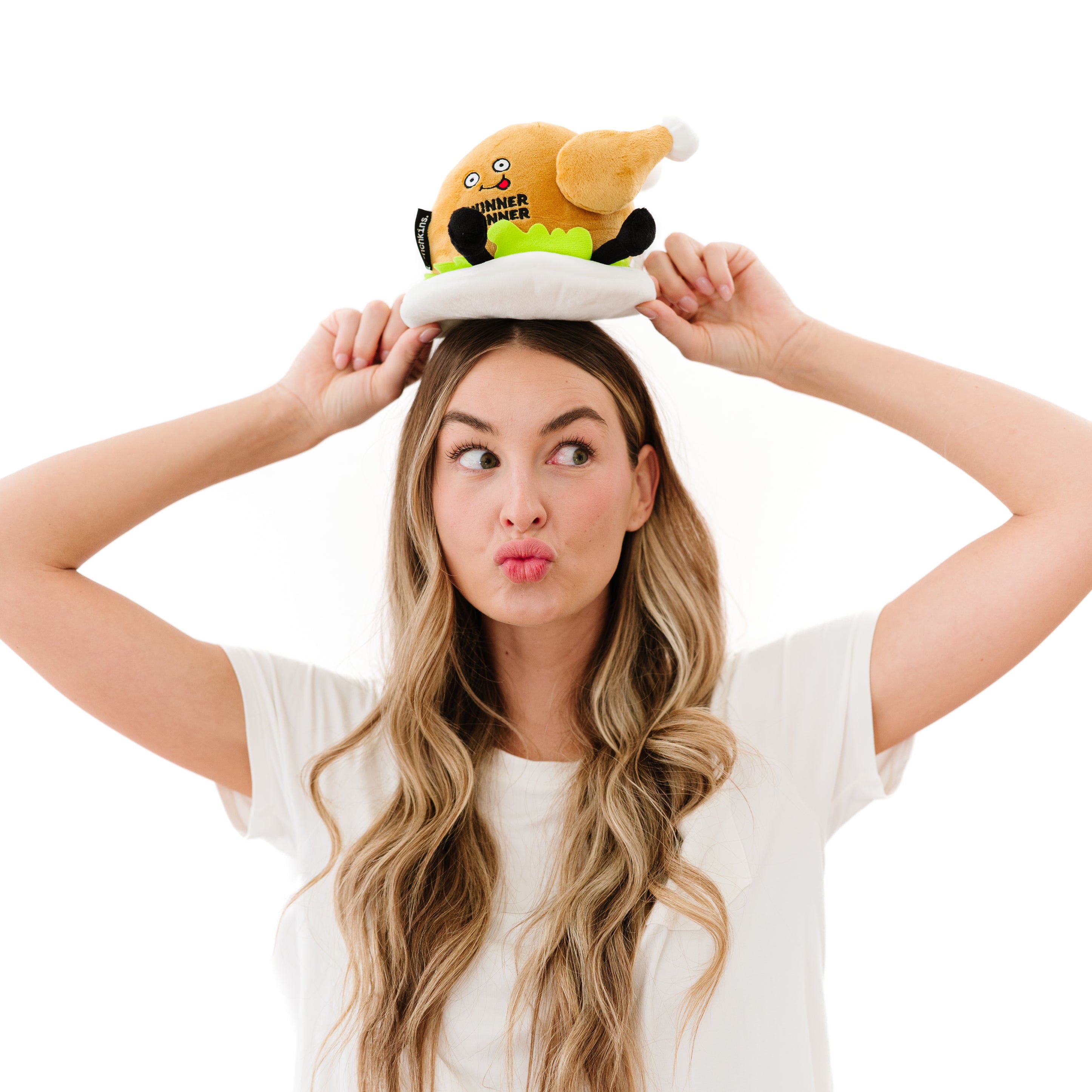 A model holding a plush designed to look like a roasted chicken with a 'Winner Winner' text on its chest and cartoonish facial features.