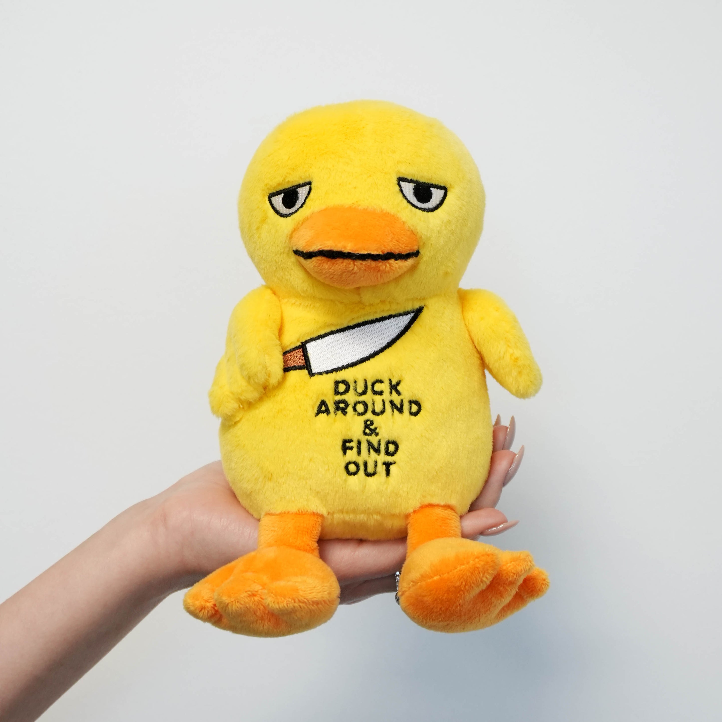 Yellow plush duck with the phrase 'duck around & find out' on a plain background