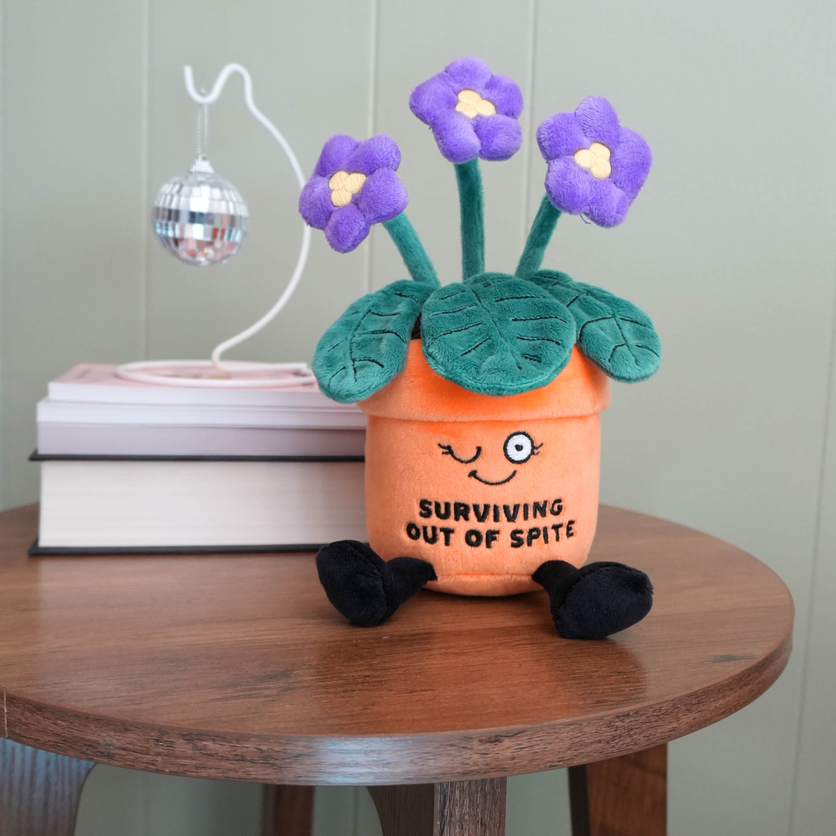 Plush flower pot with purple flowers on a wooden table