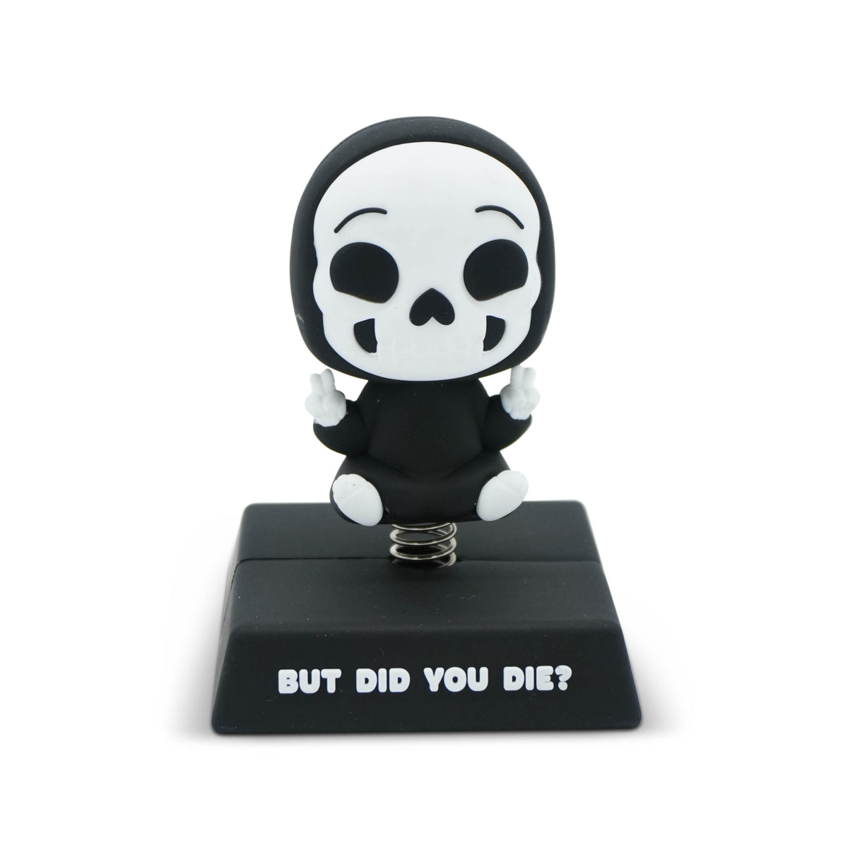 A black and white skeleton figurine sitting on a black base with the text 'BUT DID YOU DIE?' in white. The figurine has a white skull face and black body, with small white hands and legs, mounted on a metal spring.