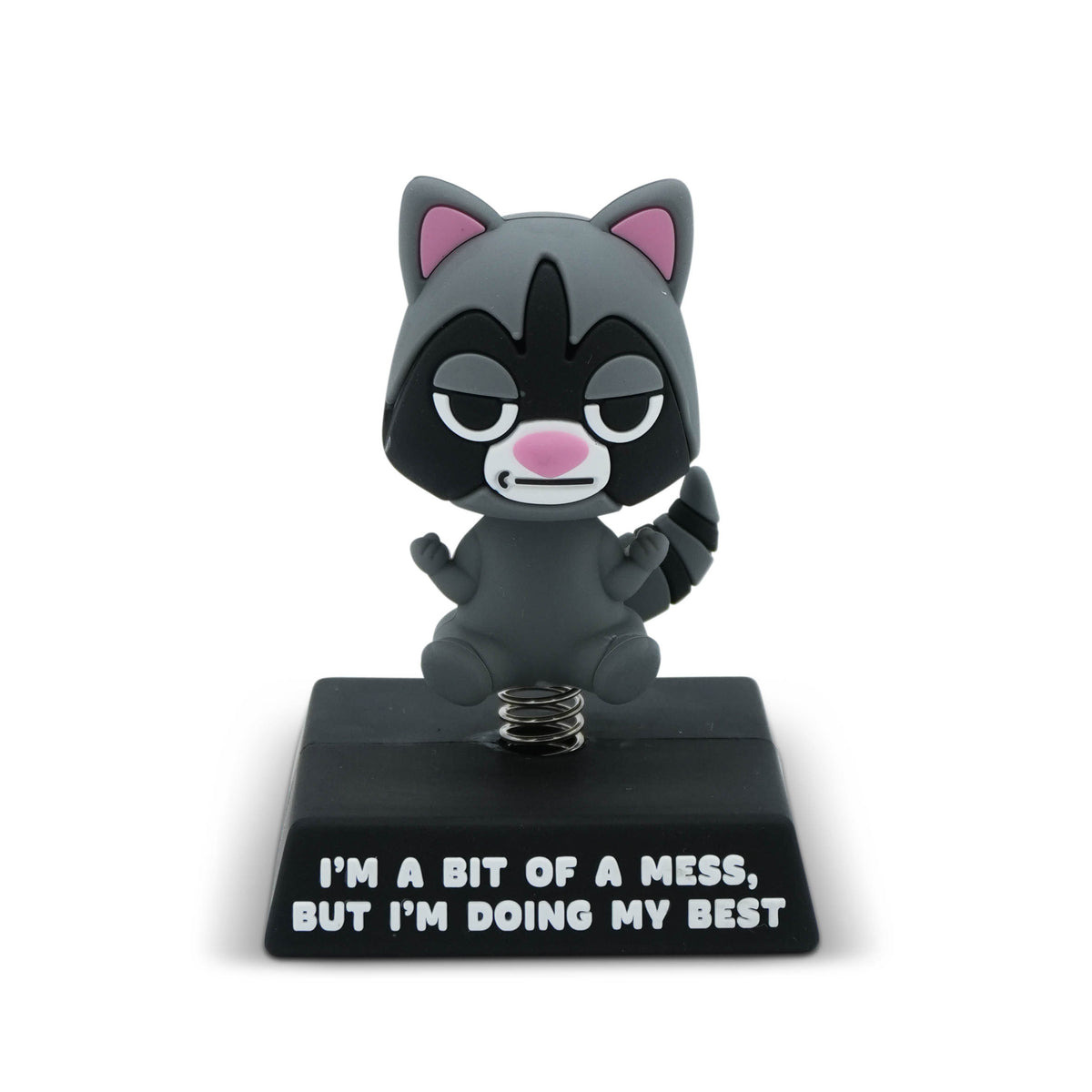 A small cartoon raccoon figurine on a black base with the text 'I'M A BIT OF A MESS, BUT I'M DOING MY BEST' on a white background.