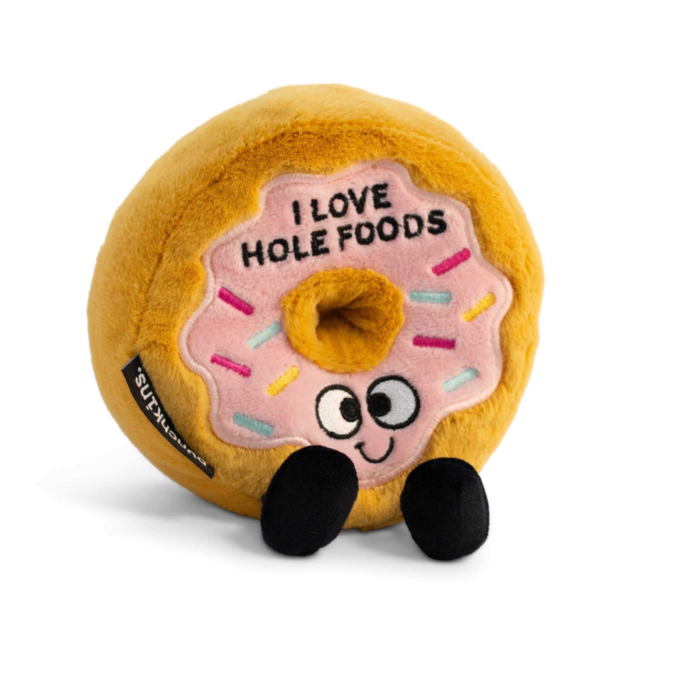 A plush designed to look like a glazed donut with sprinkles, eyes, and feet, with the text 'I LOVE HOLE FOODS' on the top.