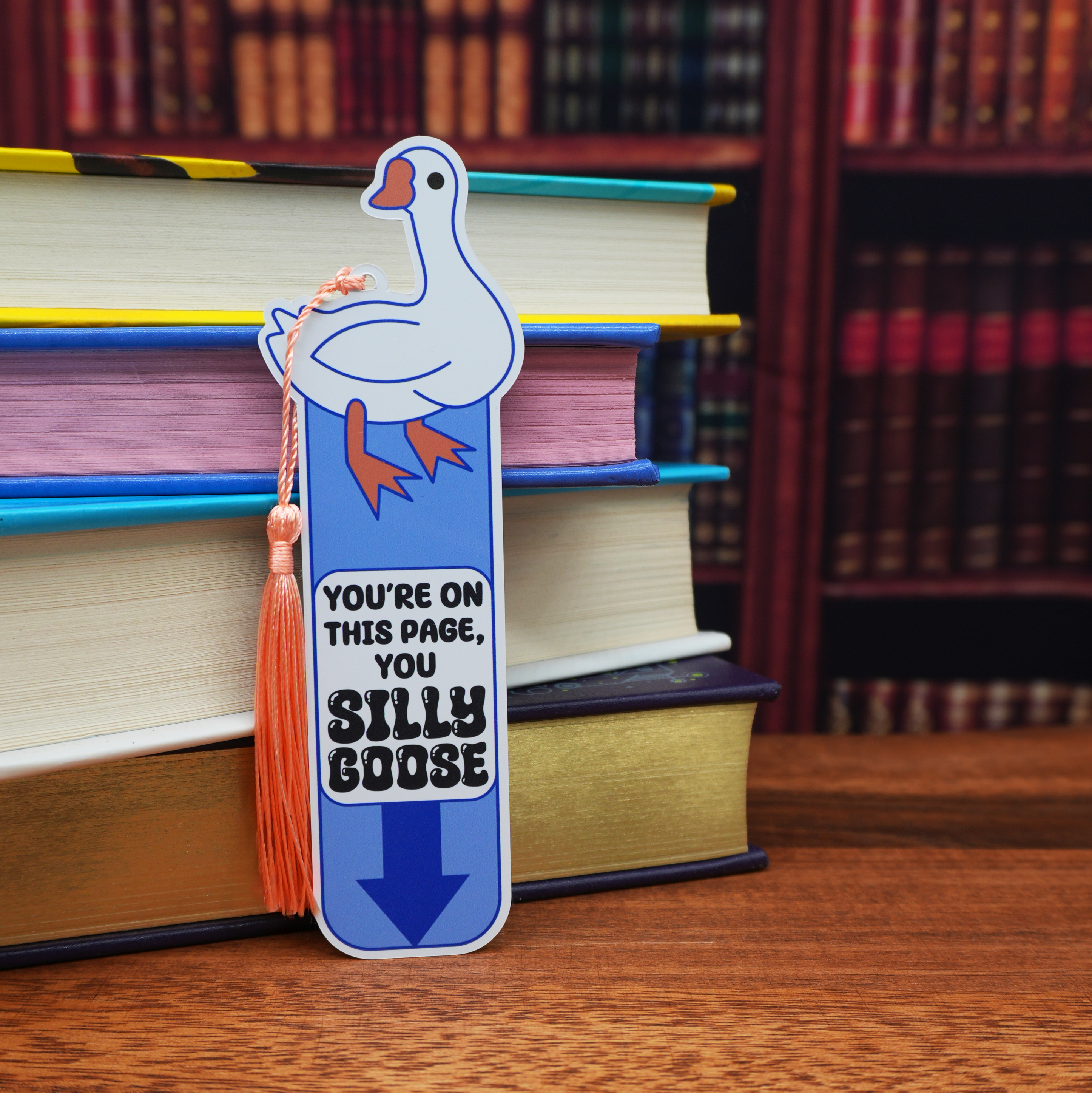 Bookmark with a cartoon goose design on a stack of books