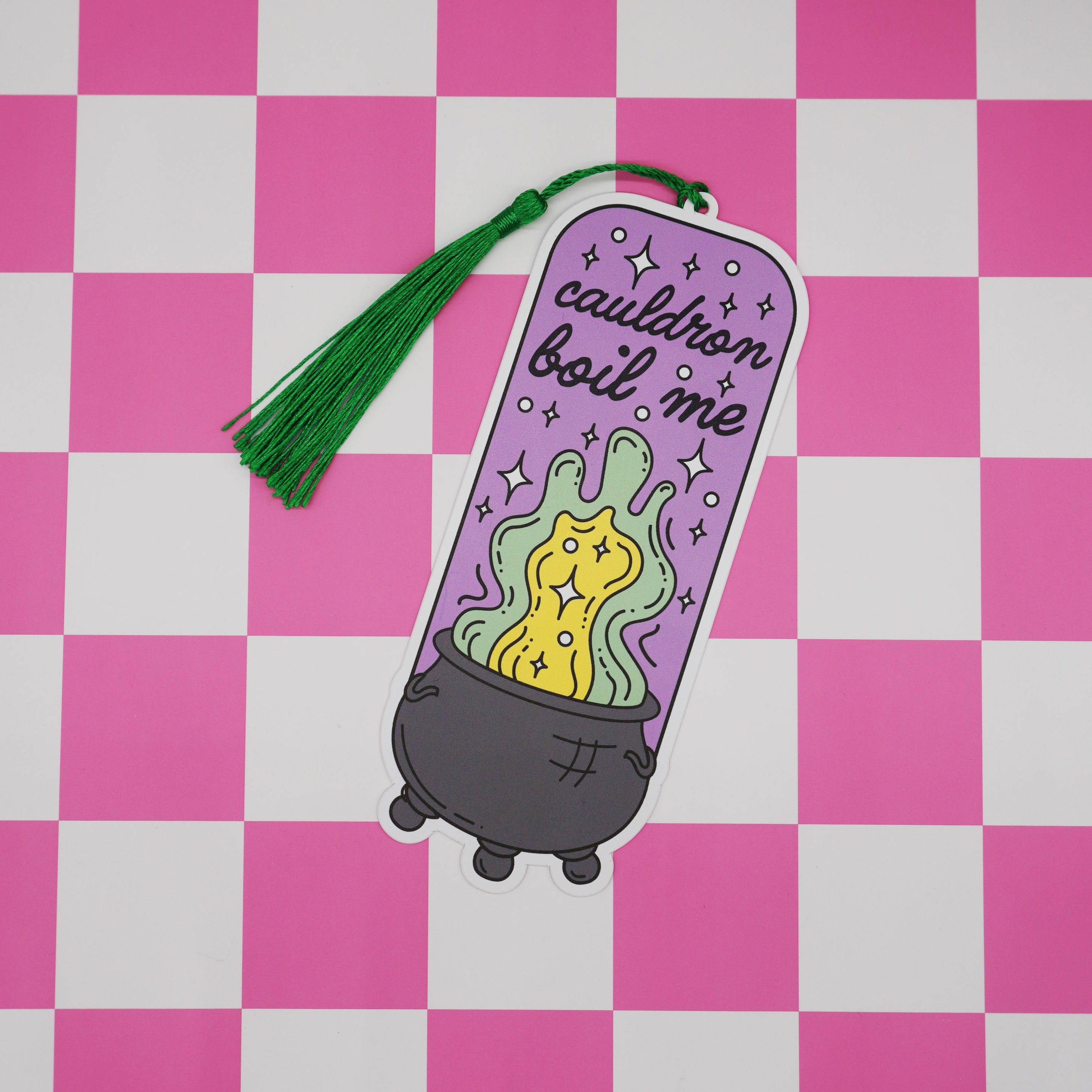 Bookmark with a cauldron boil me design and green tassel on a pink and white checkered background