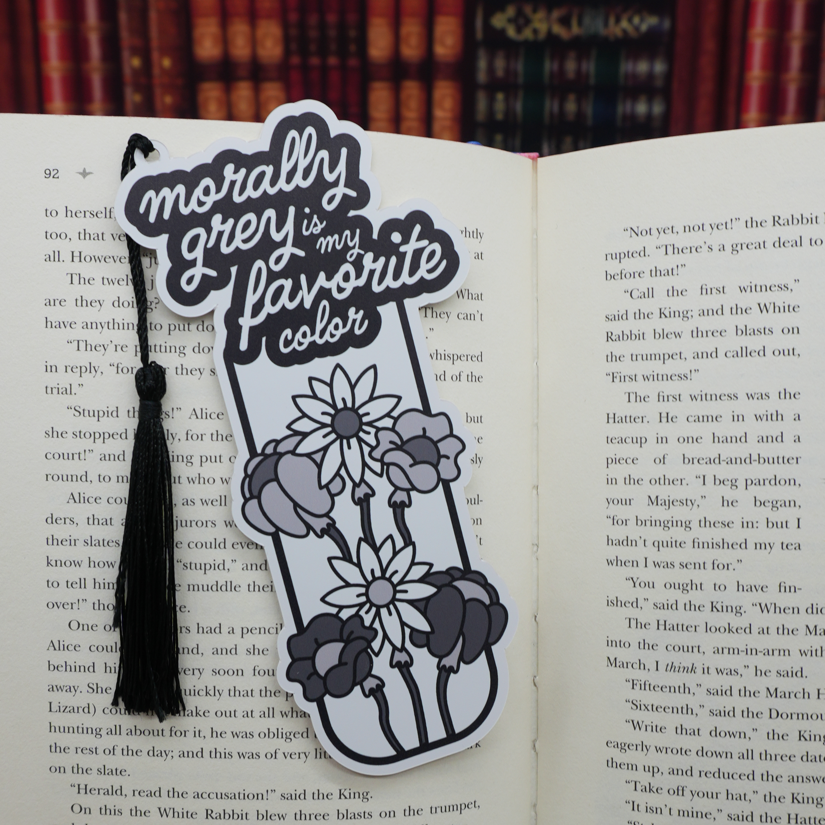 Decorative morally grey-themed bookmark with floral design and text on an open book