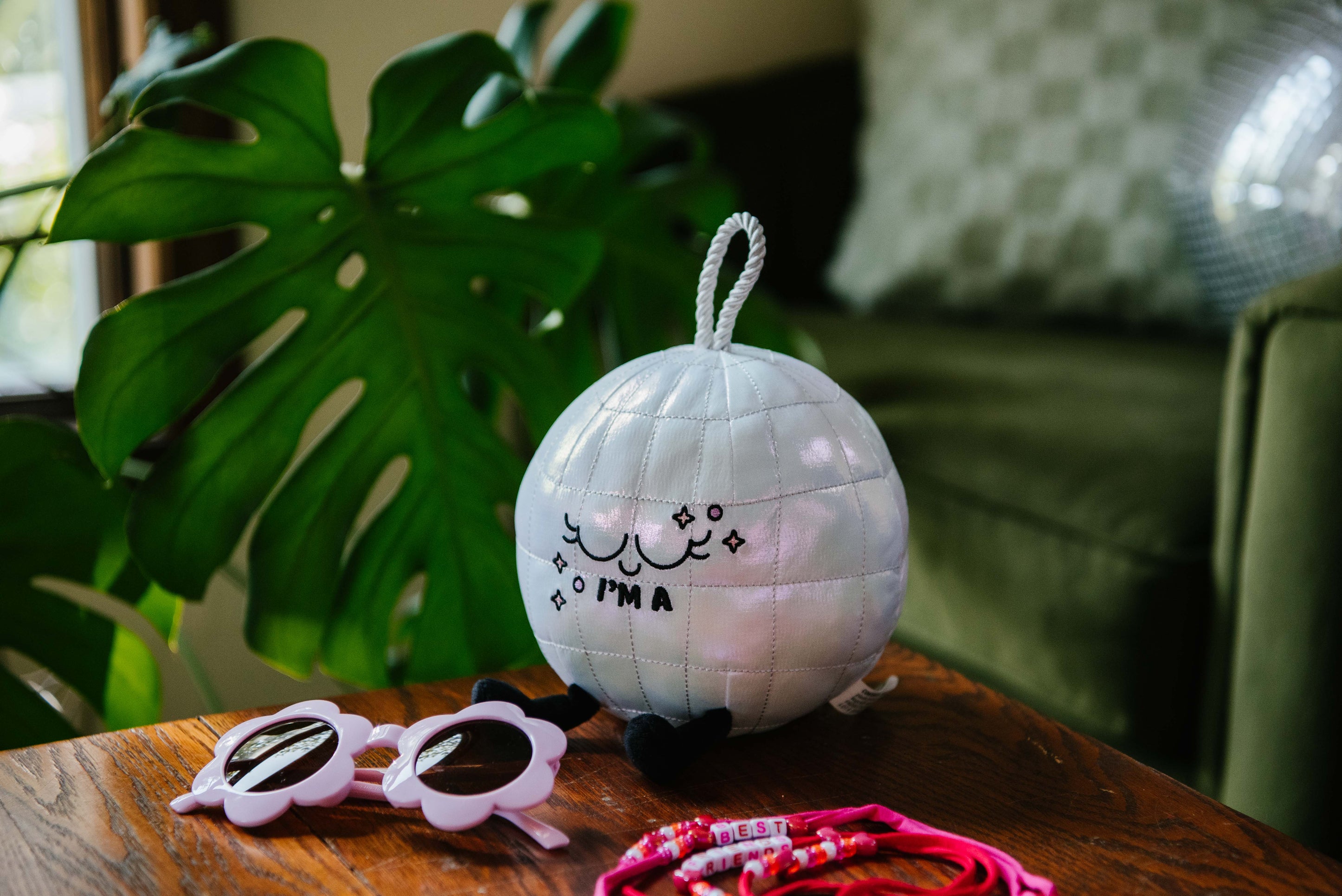 A plush resembling a disco ball with the text 'I'M A' on it placed on a couch.