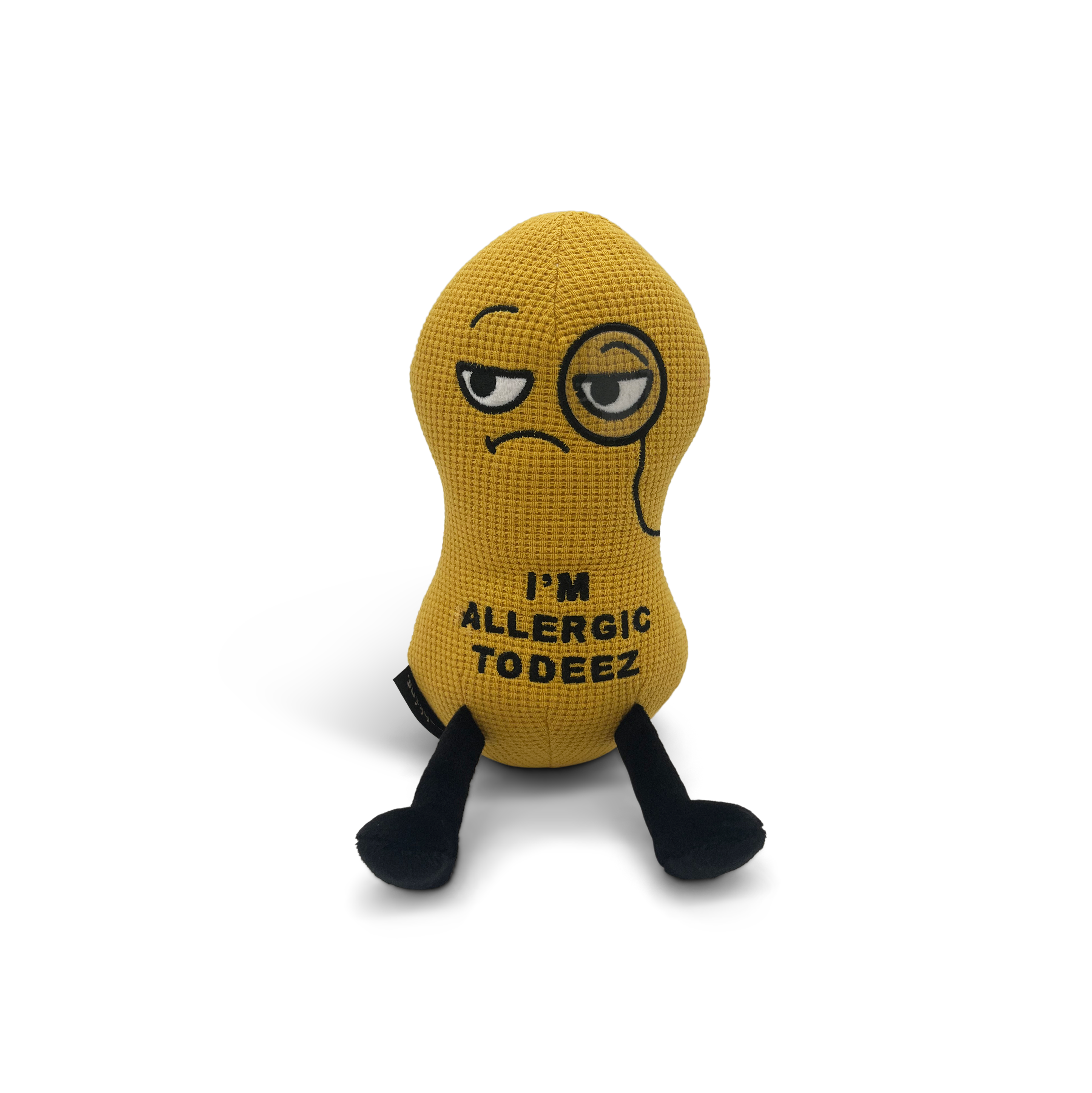 A plush shaped like a peanut with a sad facial expression and the text 'I'M ALLERGIC TO DEEZ' embroidered on its body.