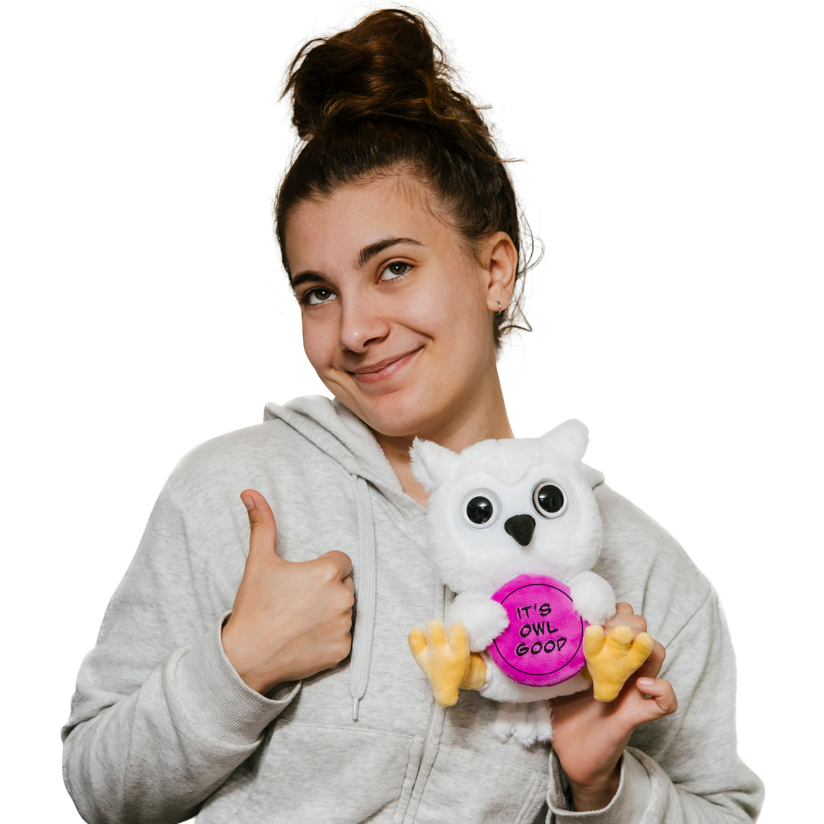 A woman holding a plush depicting an owl with large 3D eyes, holding a purple circular object with the text 'IT'S OWL GOOD'.