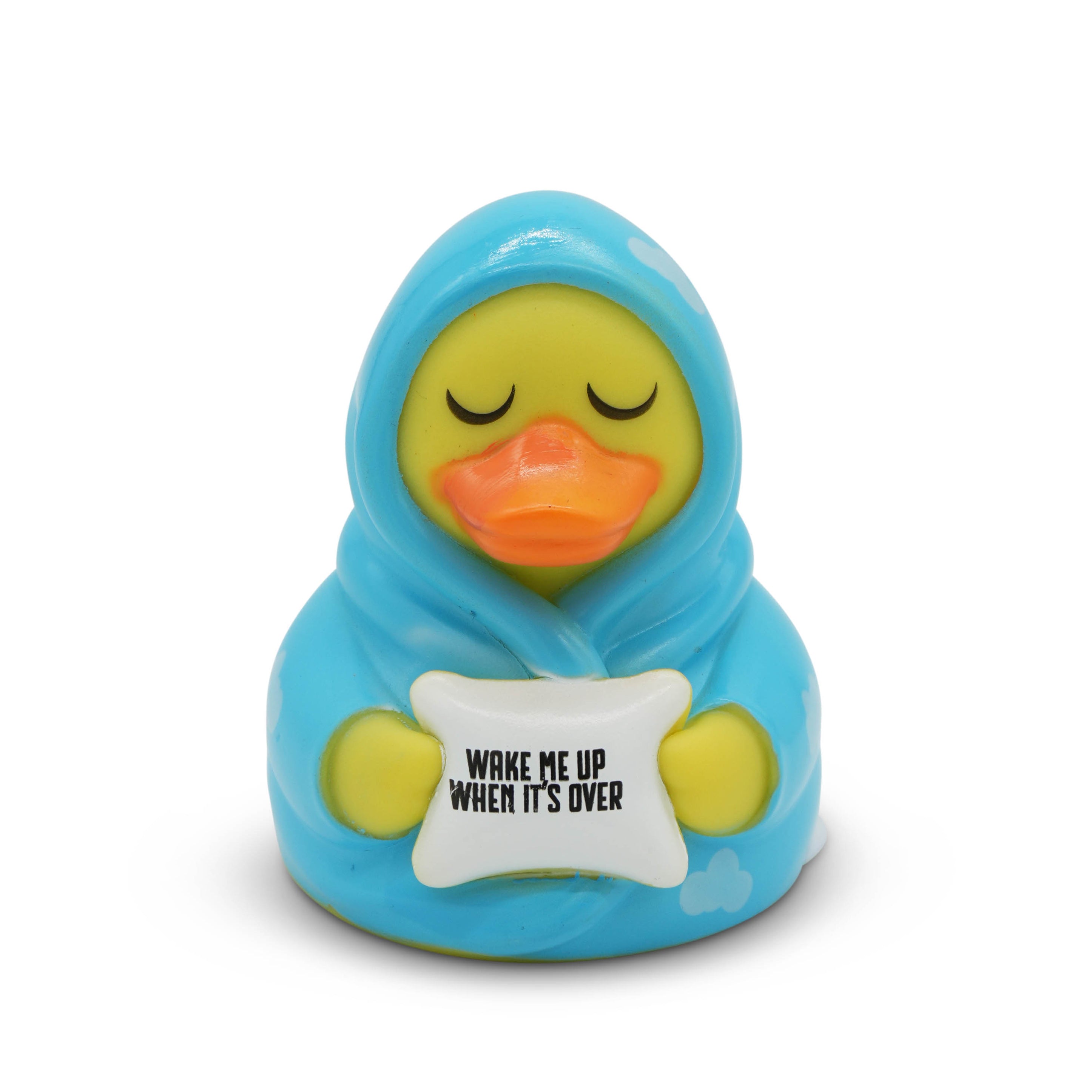 Toy duck wrapped in blue blanket with 'Wake Me Up When It's Over' pillow on white background