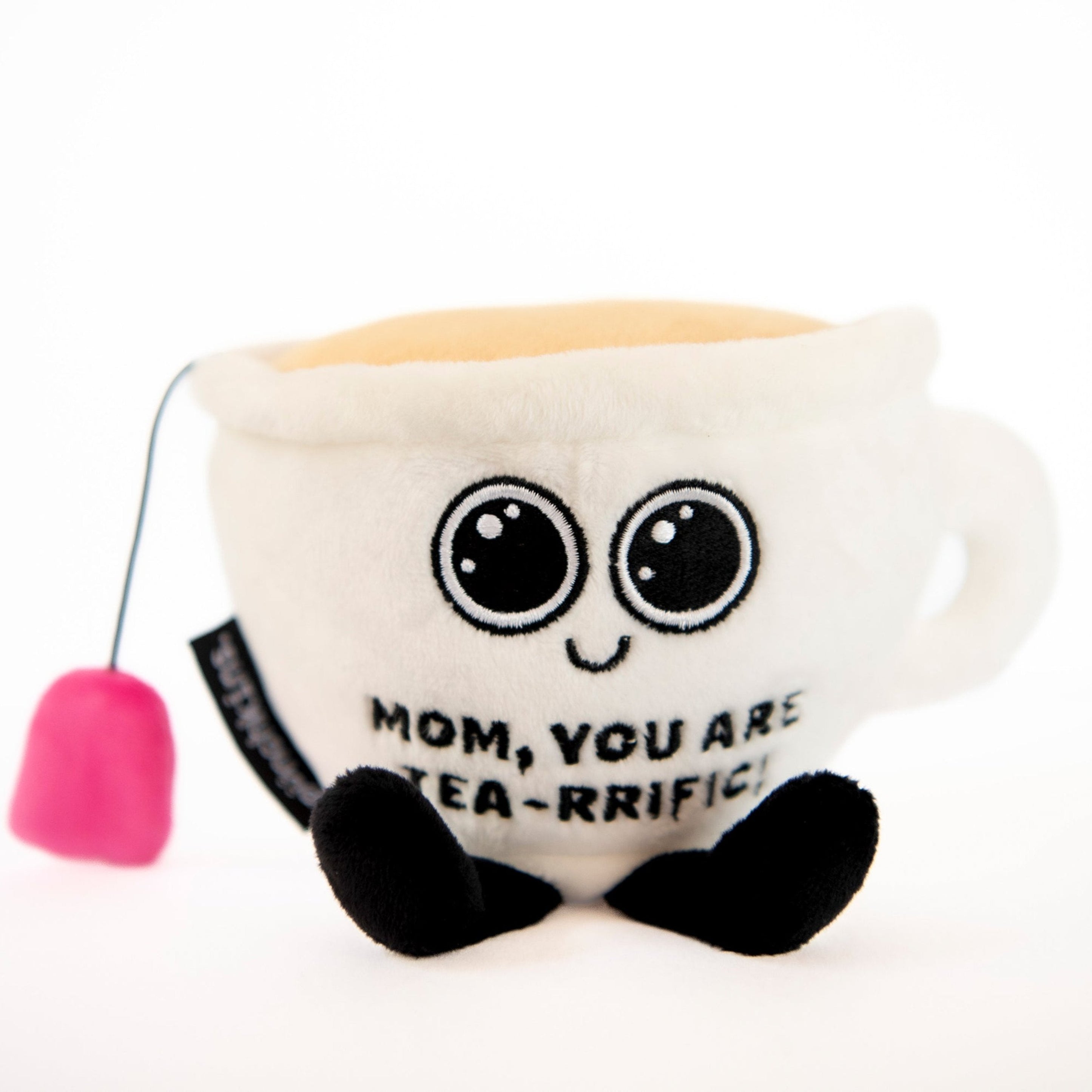 A plush shaped like a teacup with a face, eyes, a teabag hanging from its side, and the text 'MOM, YOU ARE TEA-RRIFIC' is visible on it.