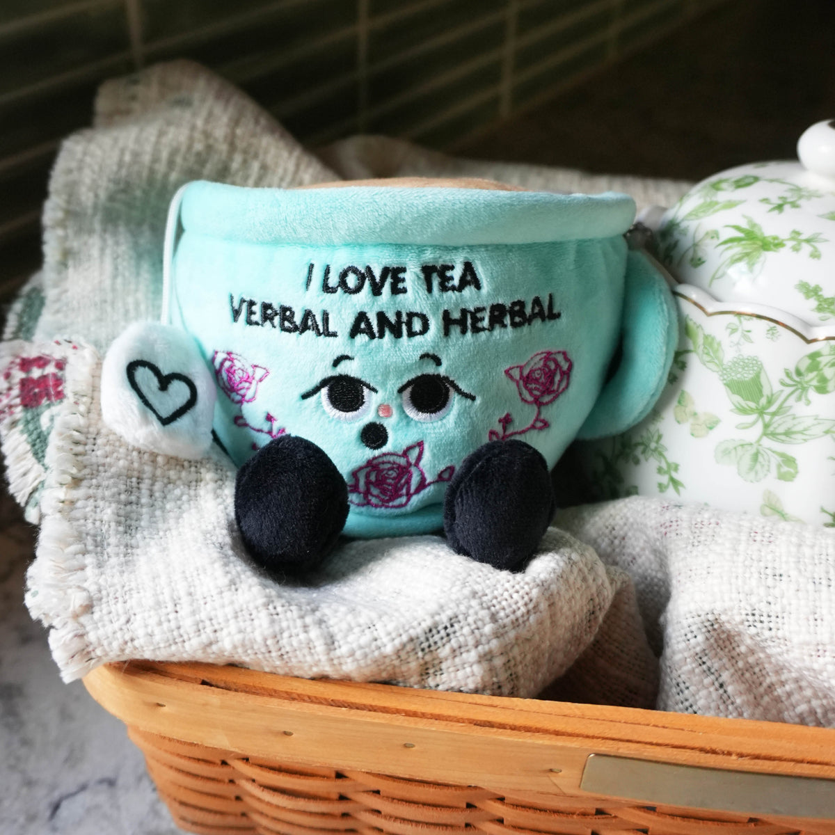 Tea cup plush toy with text 'I love tea verbal and herbal' in a woven basket.