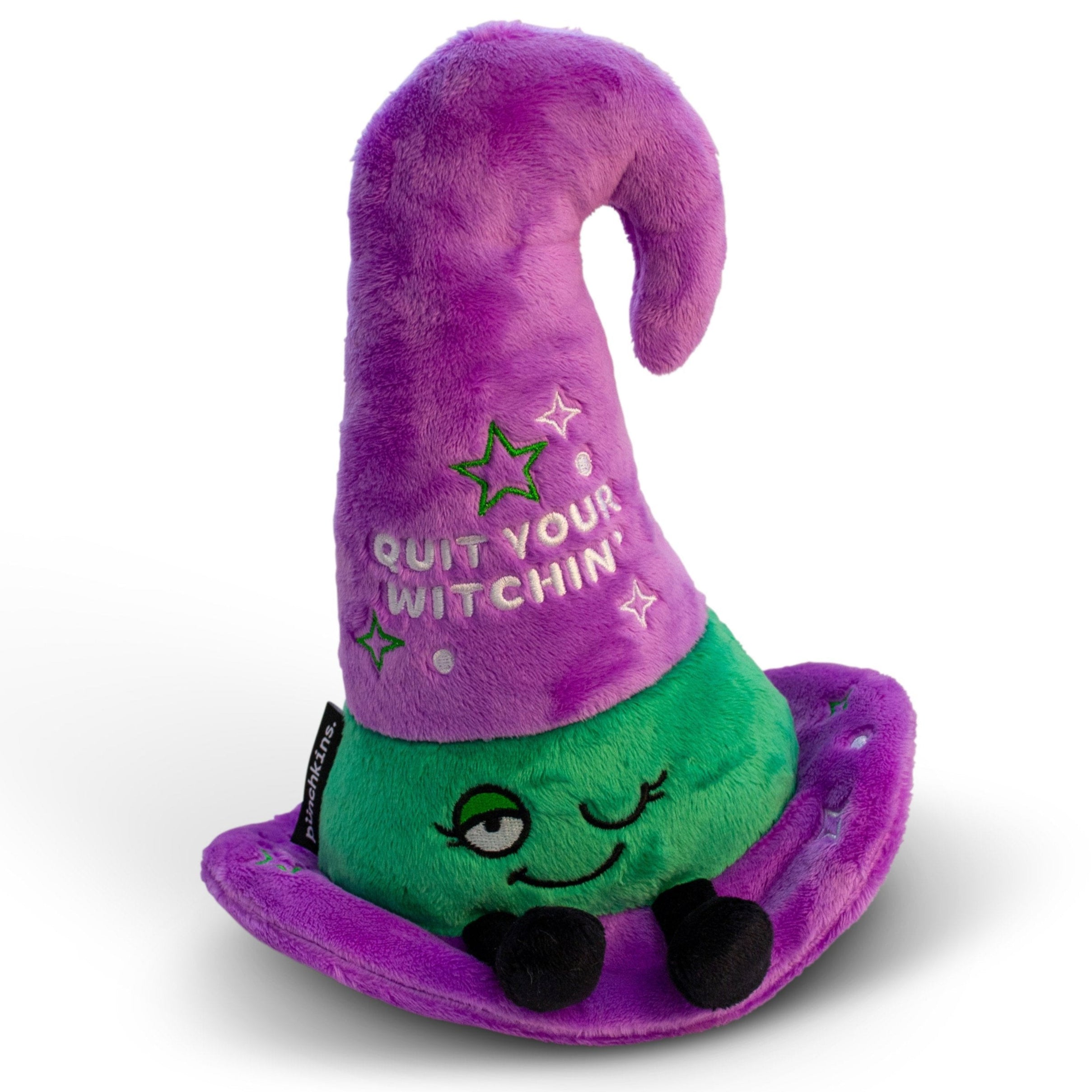 A plush witch hat with a purple brim and green crown, featuring text and star decorations. It reads, "quit your witching'."