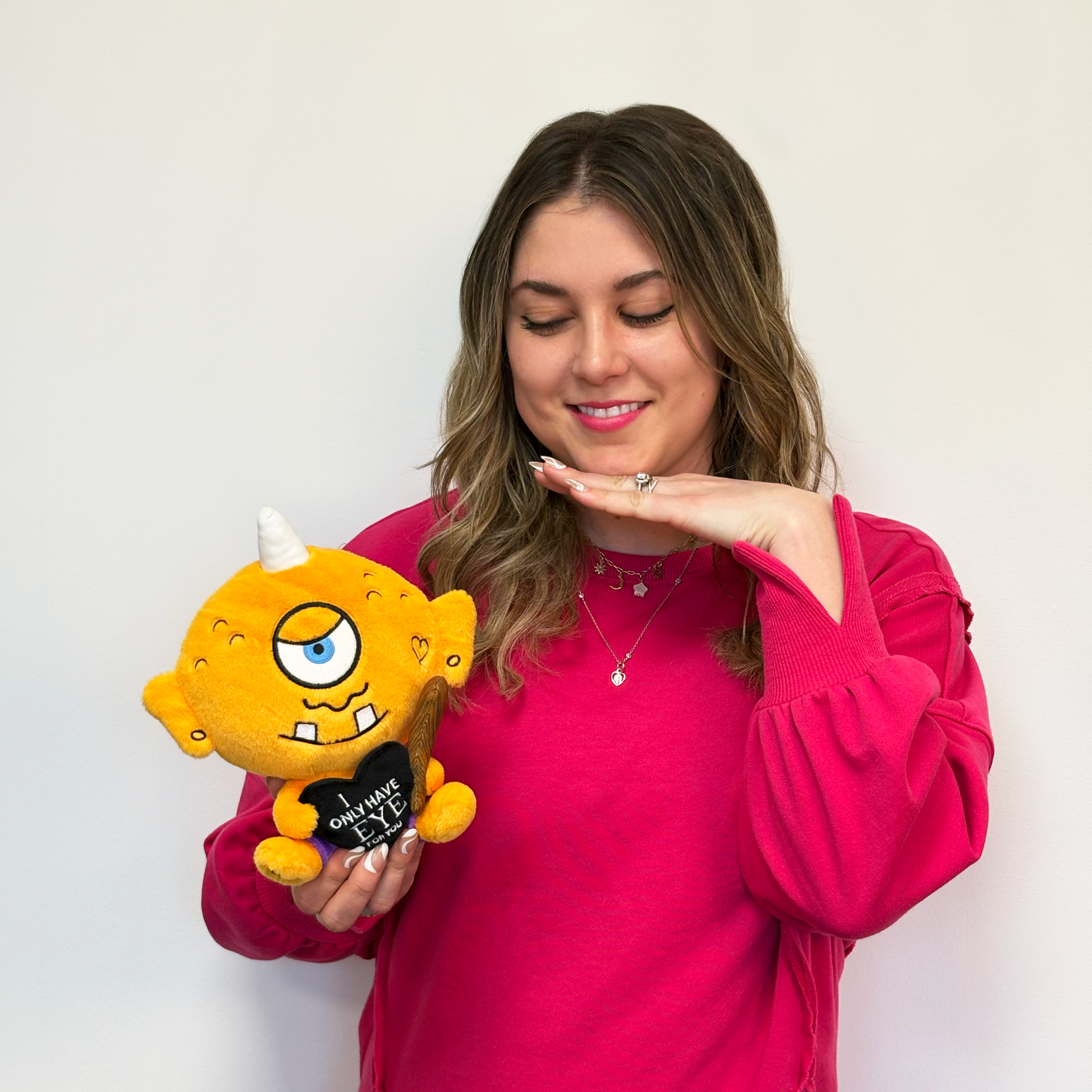 Person holding a cyclops plush toy that reads, "I only have eye for you."
