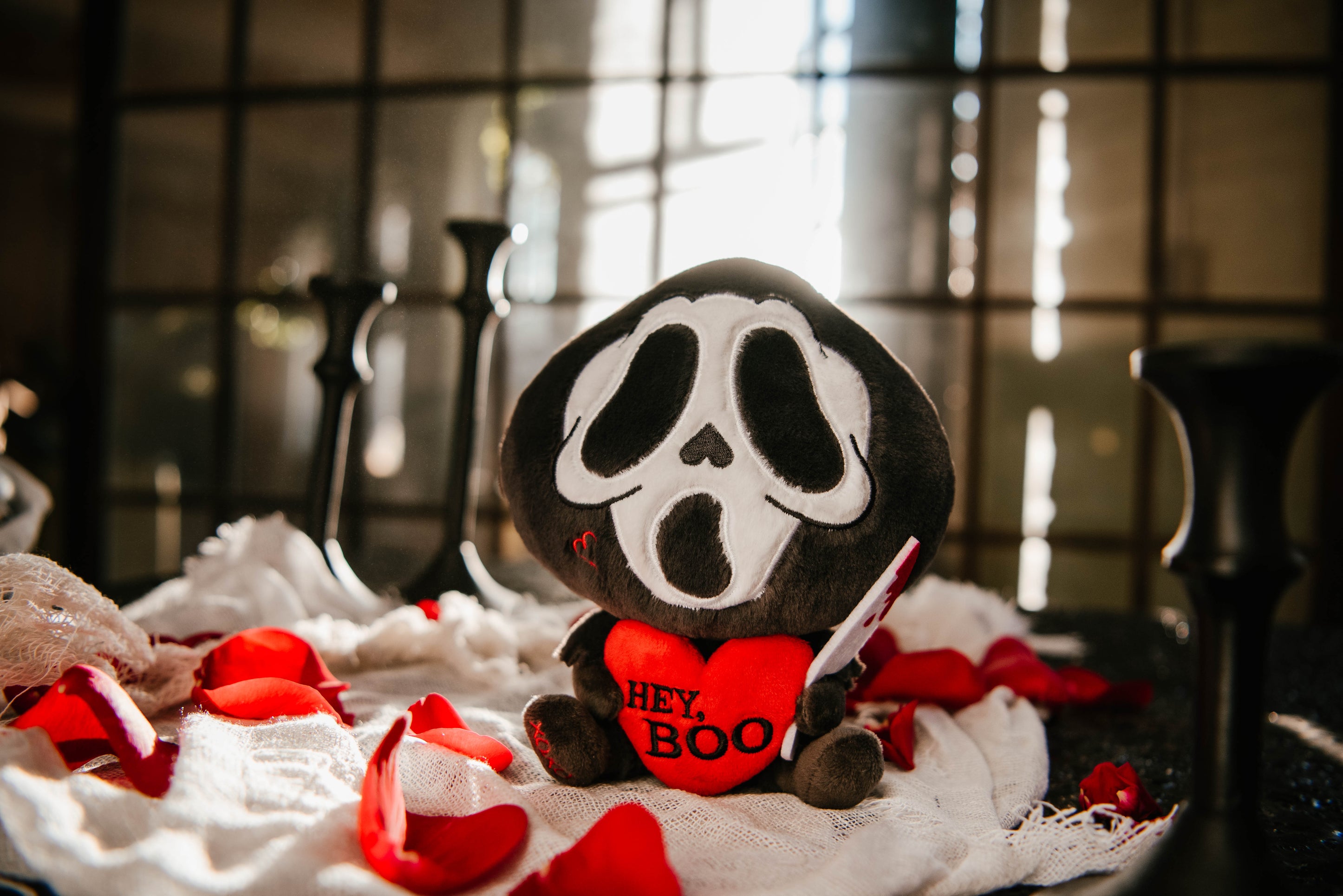 Ghost face killer plush sitting on a bed of roses