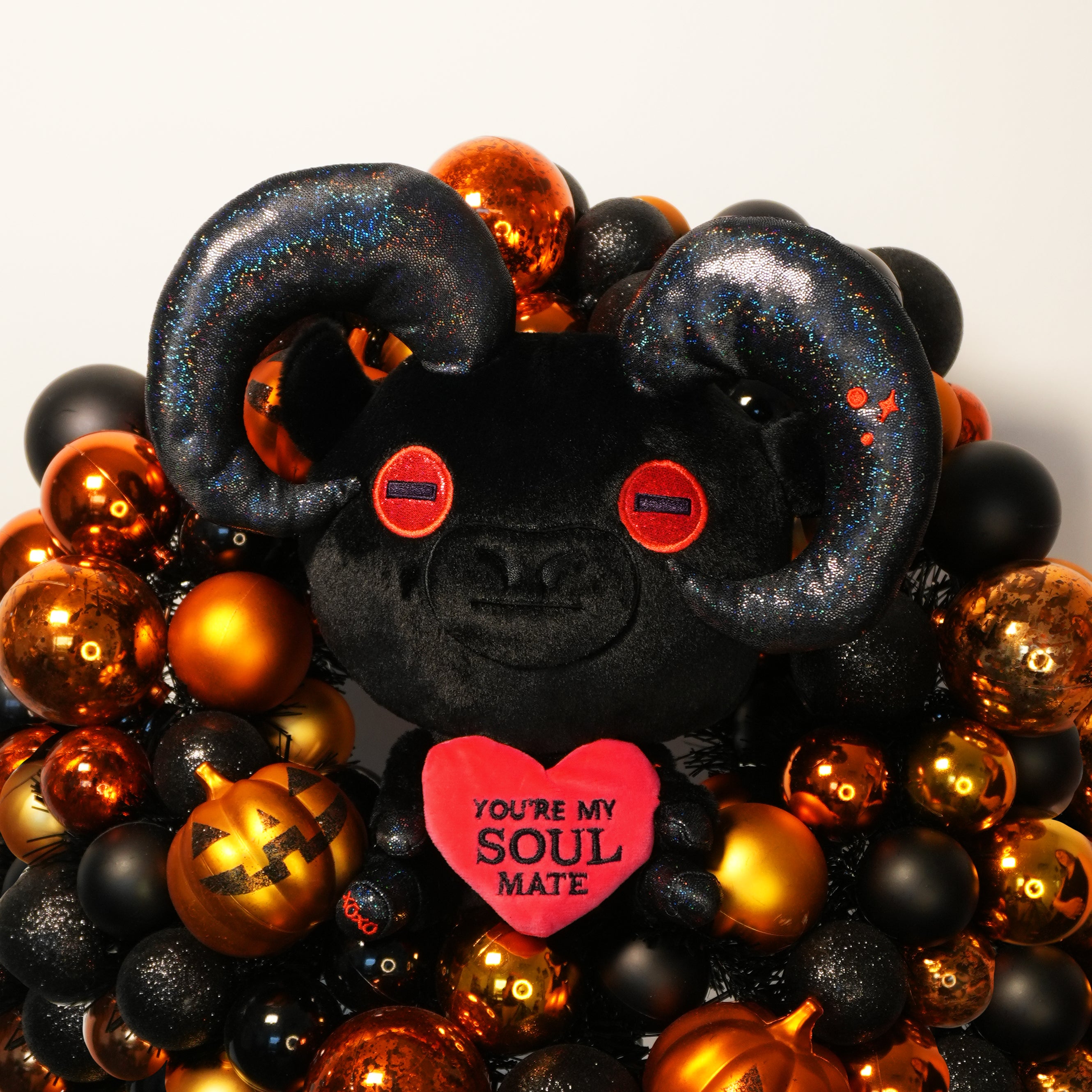 Black plush devil goat toy with red heart and 'You're My Soul Mate' text, surrounded by orange and black ornaments.