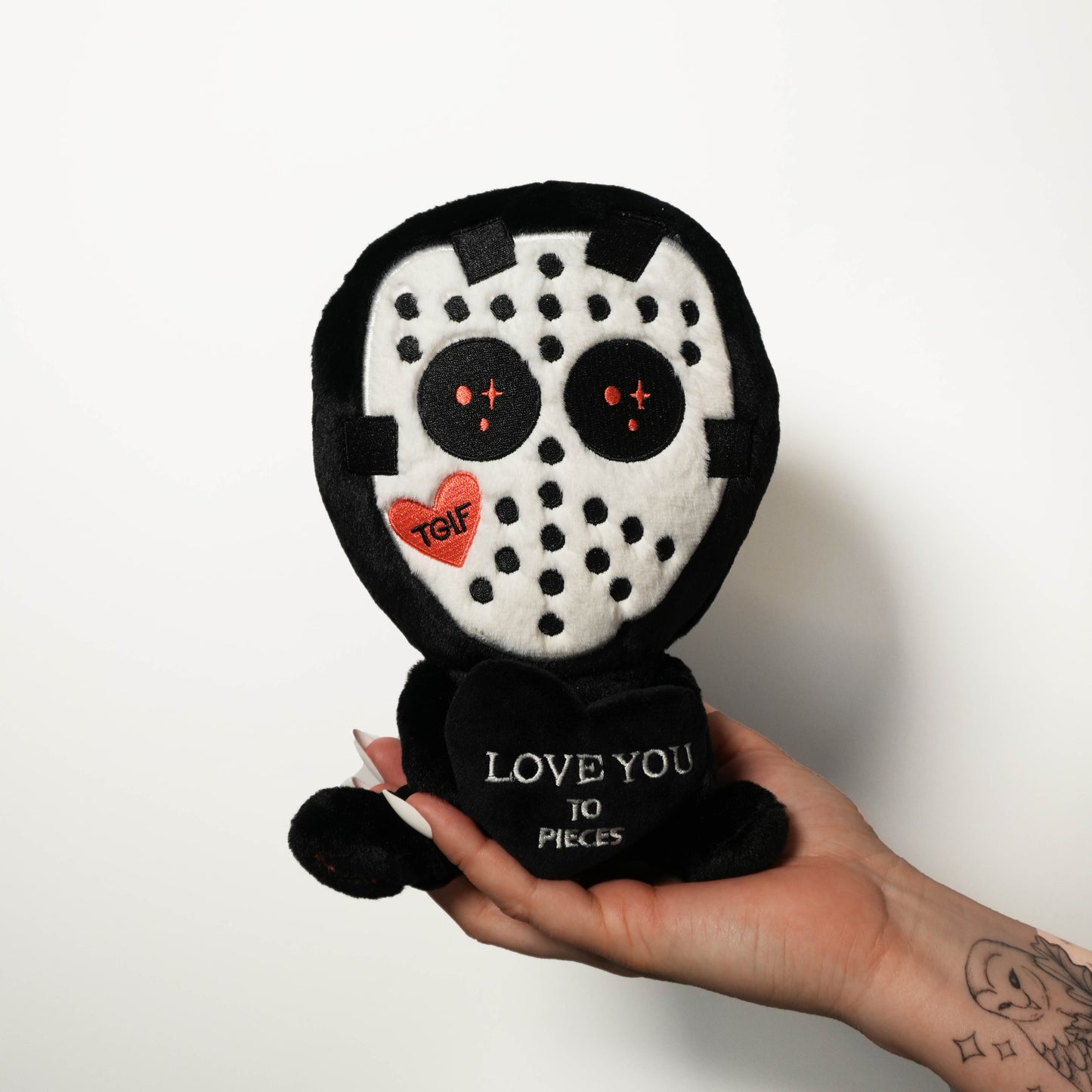 Hockey mask killer plsuh held by a hand on a white background.