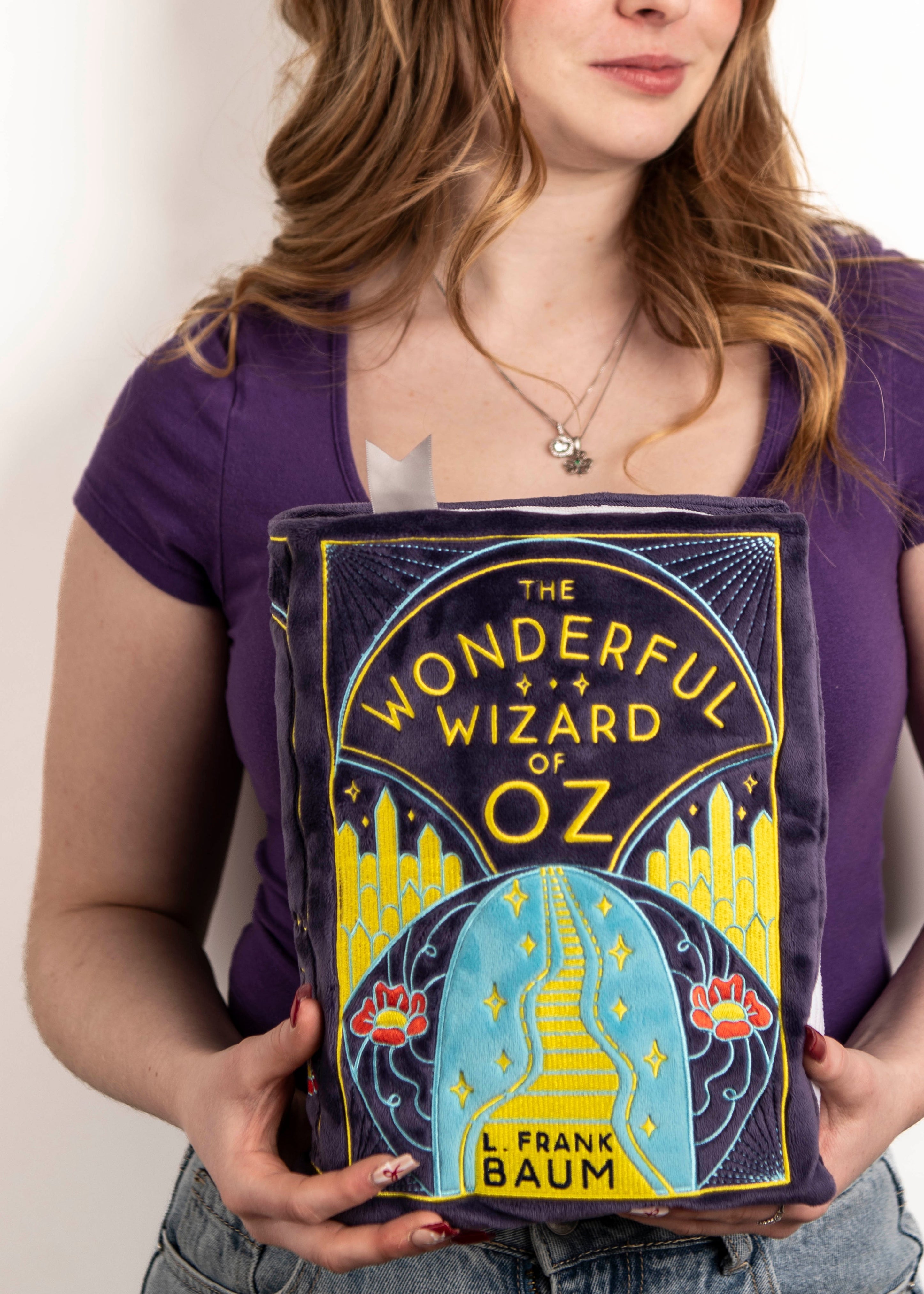 Woman holding the wizard of oz book plushie 