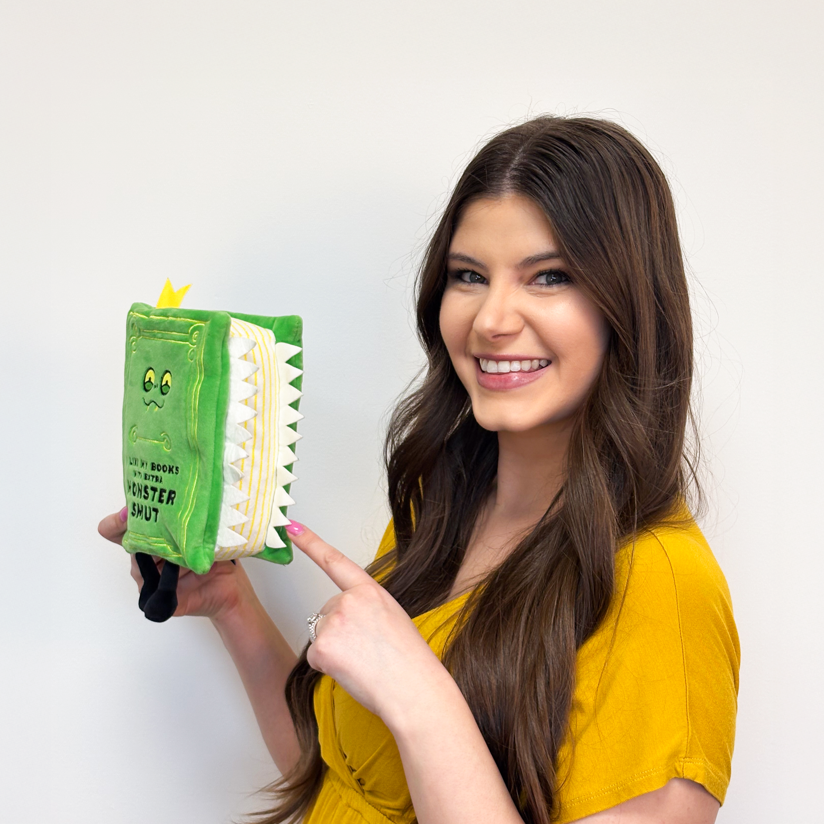 Brunette showing off 3D felt teeth on side of monster smut book plush