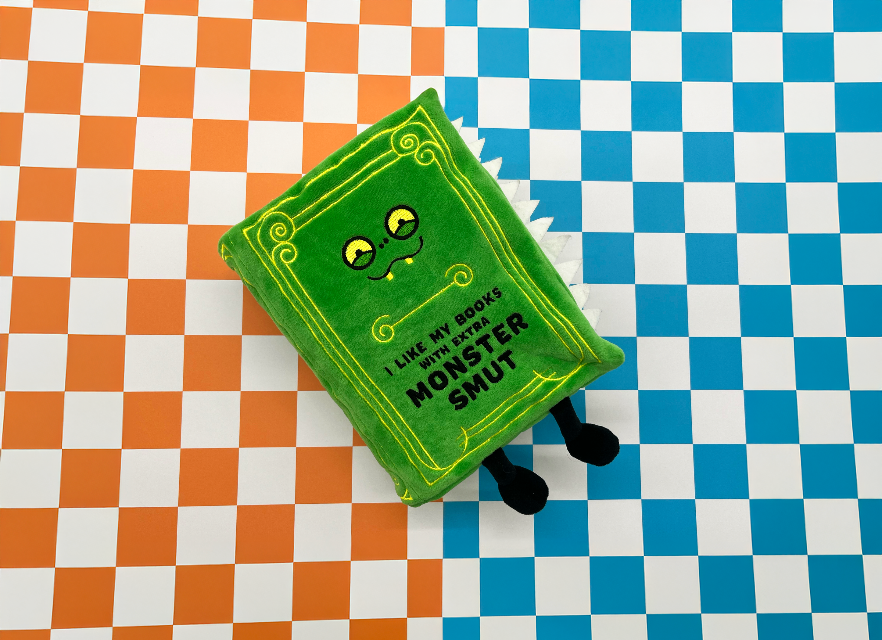 A plush monster smut book on checkered background 