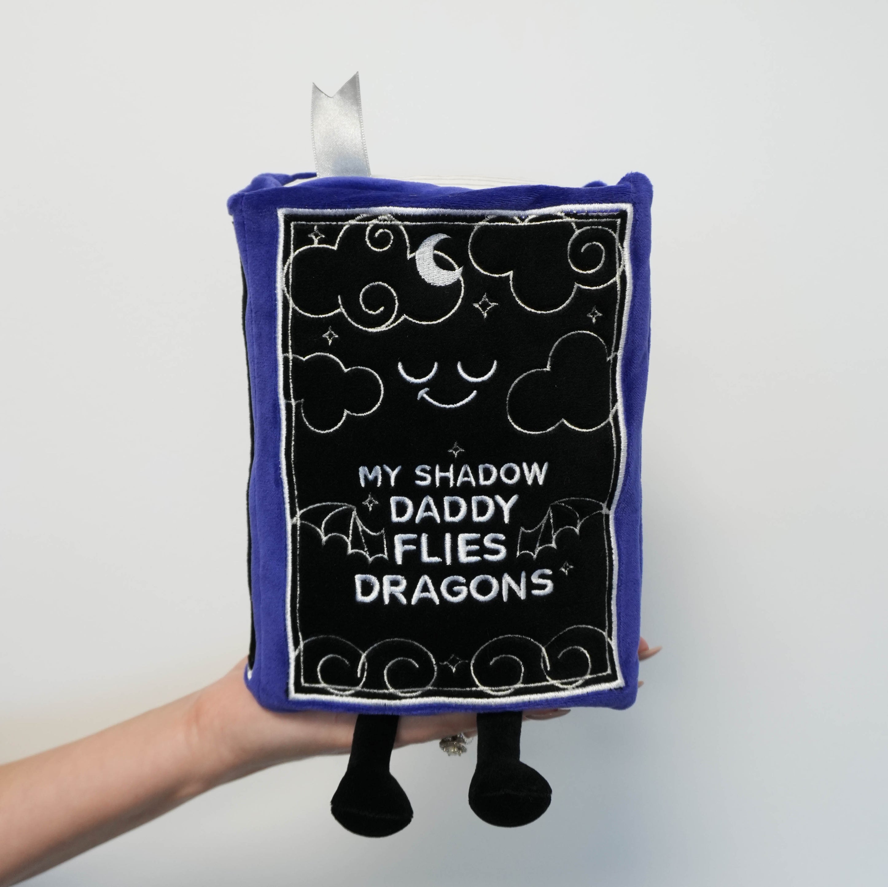 Plush shaped like a book with 'My shadow daddy flies dragons' text on a white background