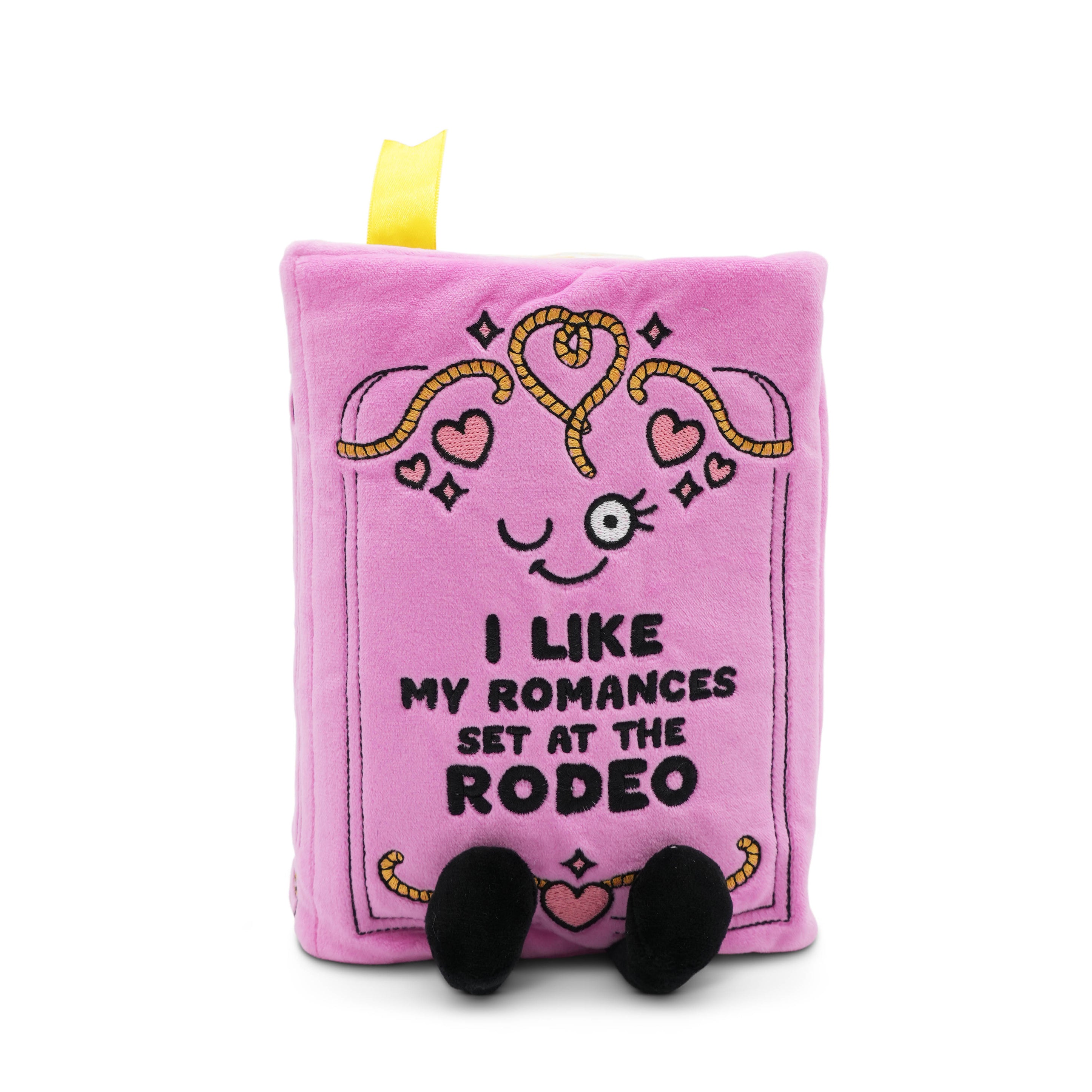 Pink plush book with a face and 'I like my romances set at the rodeo' text on a white background