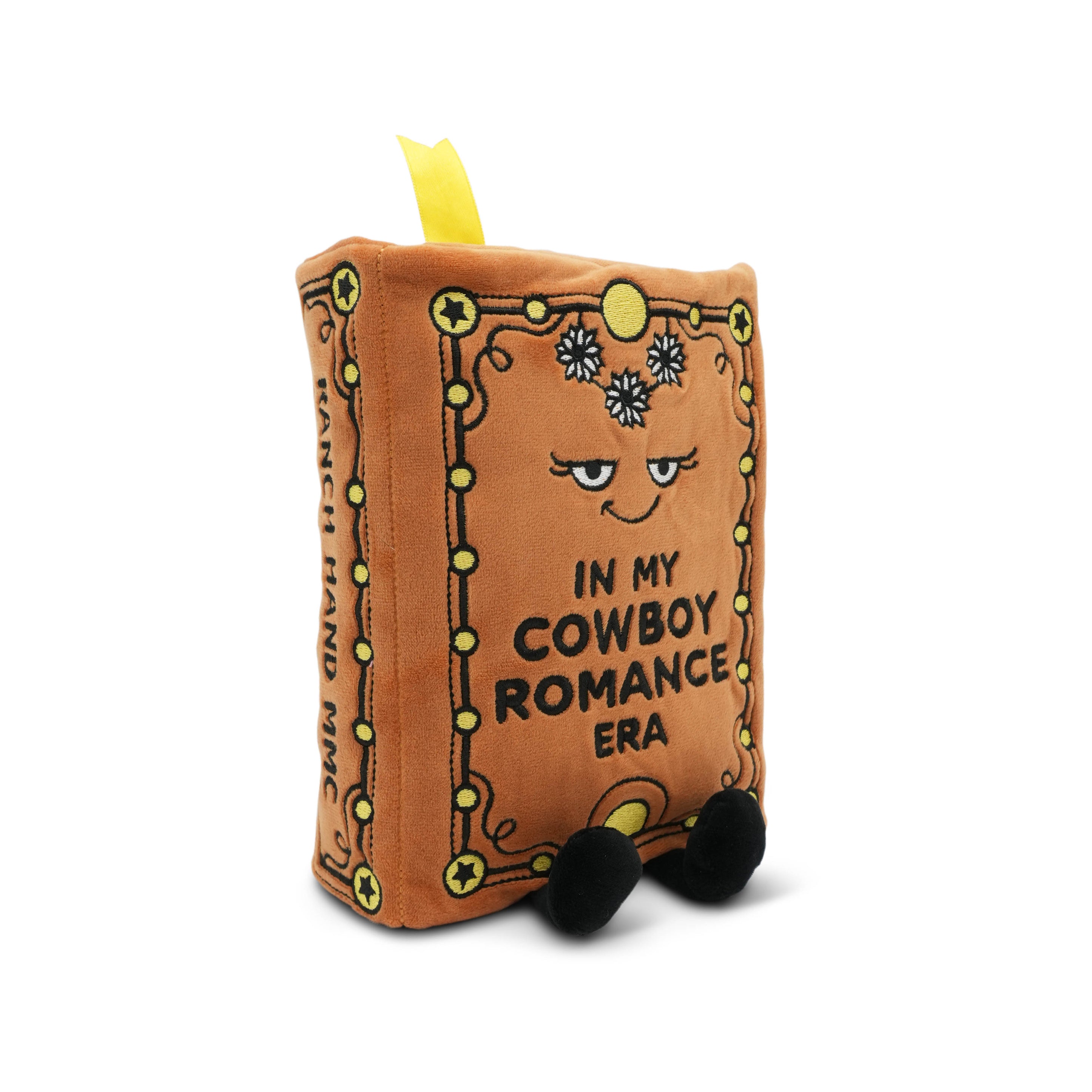 Plush book with a face and text 'In my cowboy romance era' on a white background