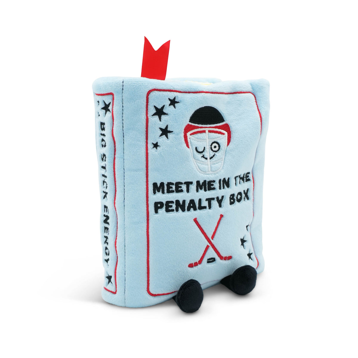 A light blue plush toy shaped like a book with embroidered details, including a goalie face, hockey stick, stars, and the text 'MEET ME IN THE PENALTY BOX' on the front, with 'BIG STICK ENERGY' on the side. It has a red ribbon bookmark at the top and feet.
