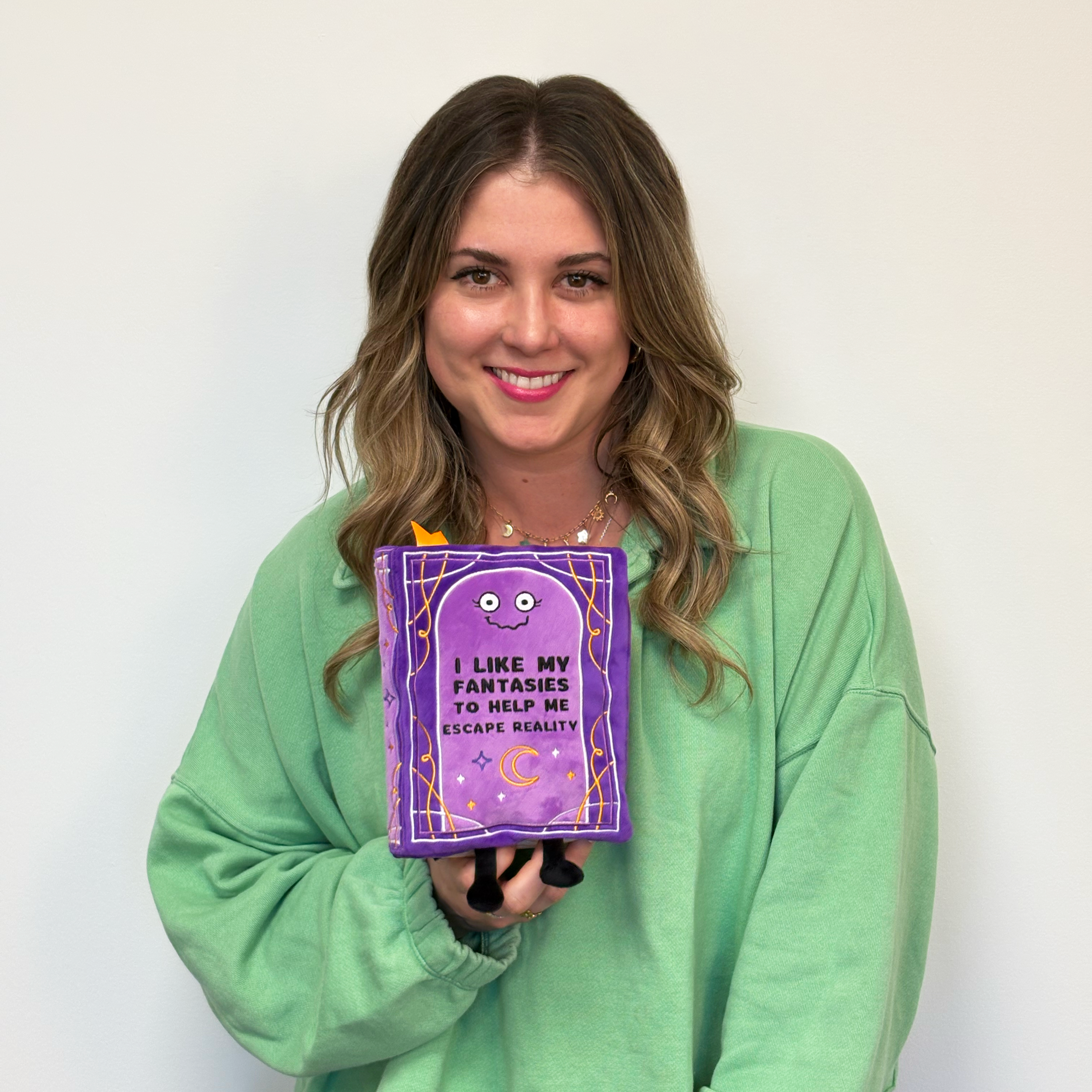 Blonde woman holding fantasy book plush