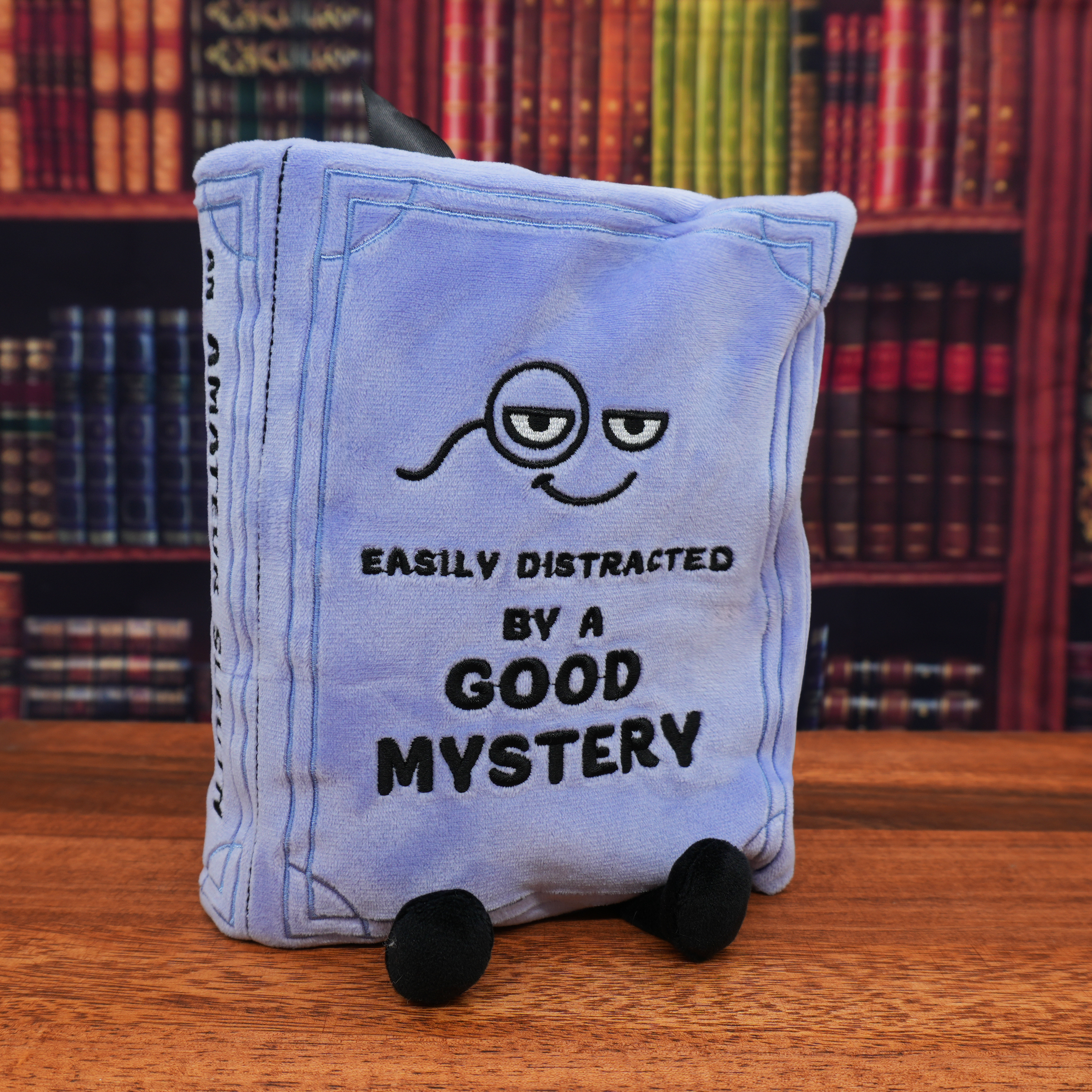 Mystery book plush in front of library wall