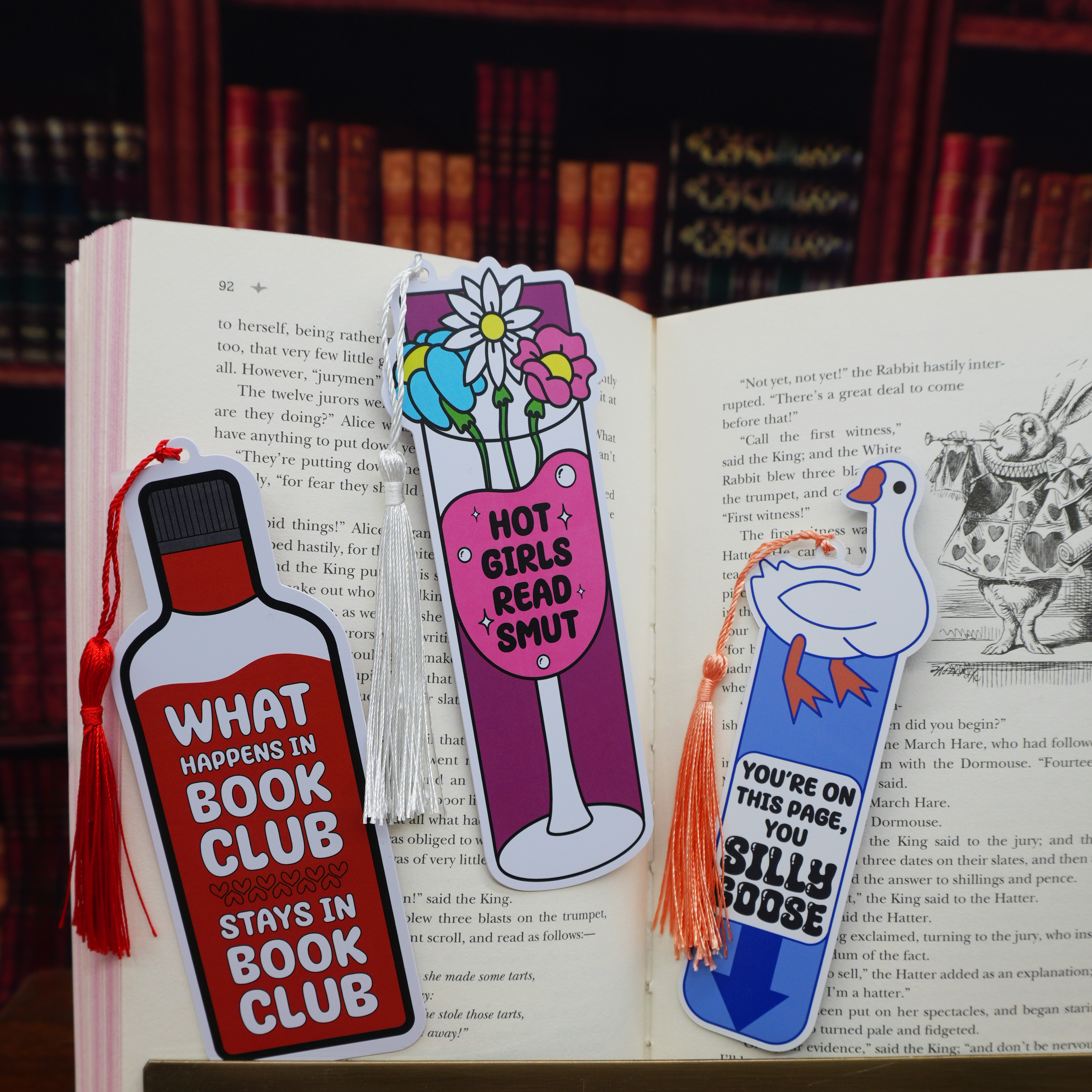Three colorful bookmarks on an open book with a bookshelf background