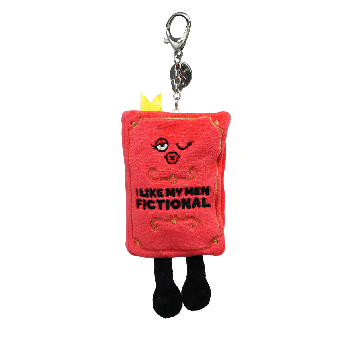 Red plush book-shaped bag charm with cartoon face and 'I like my men fictional' text on a white background