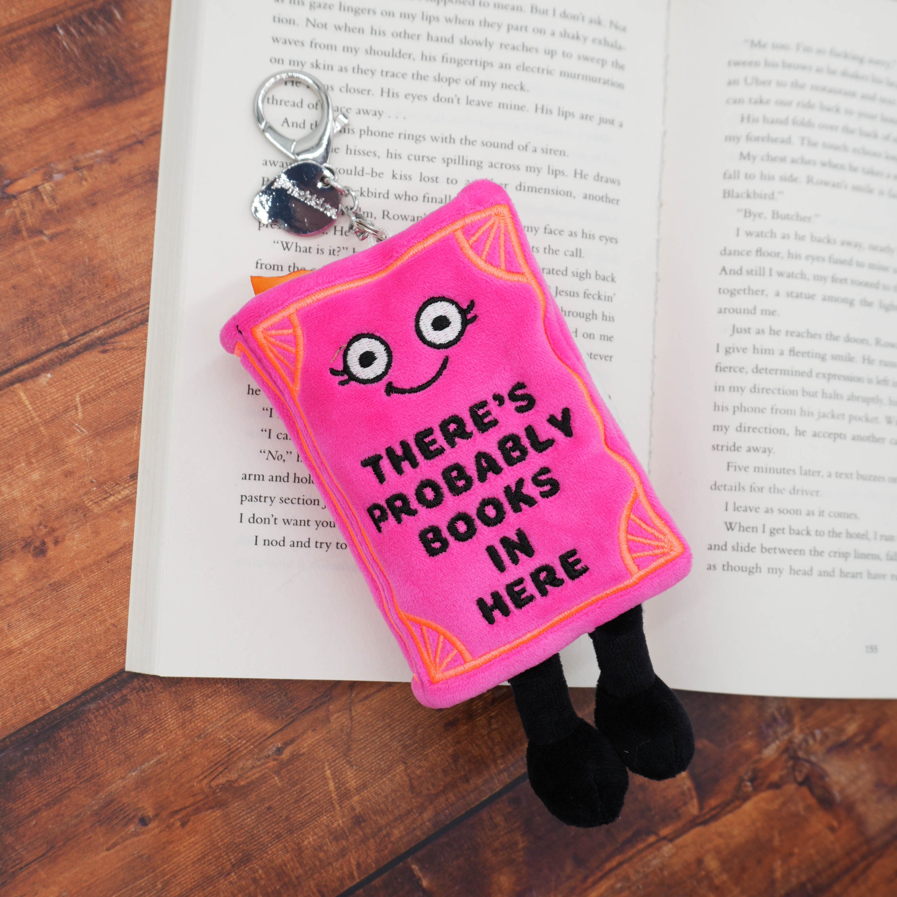 Pink plush book-shaped bag charm on a wooden surface