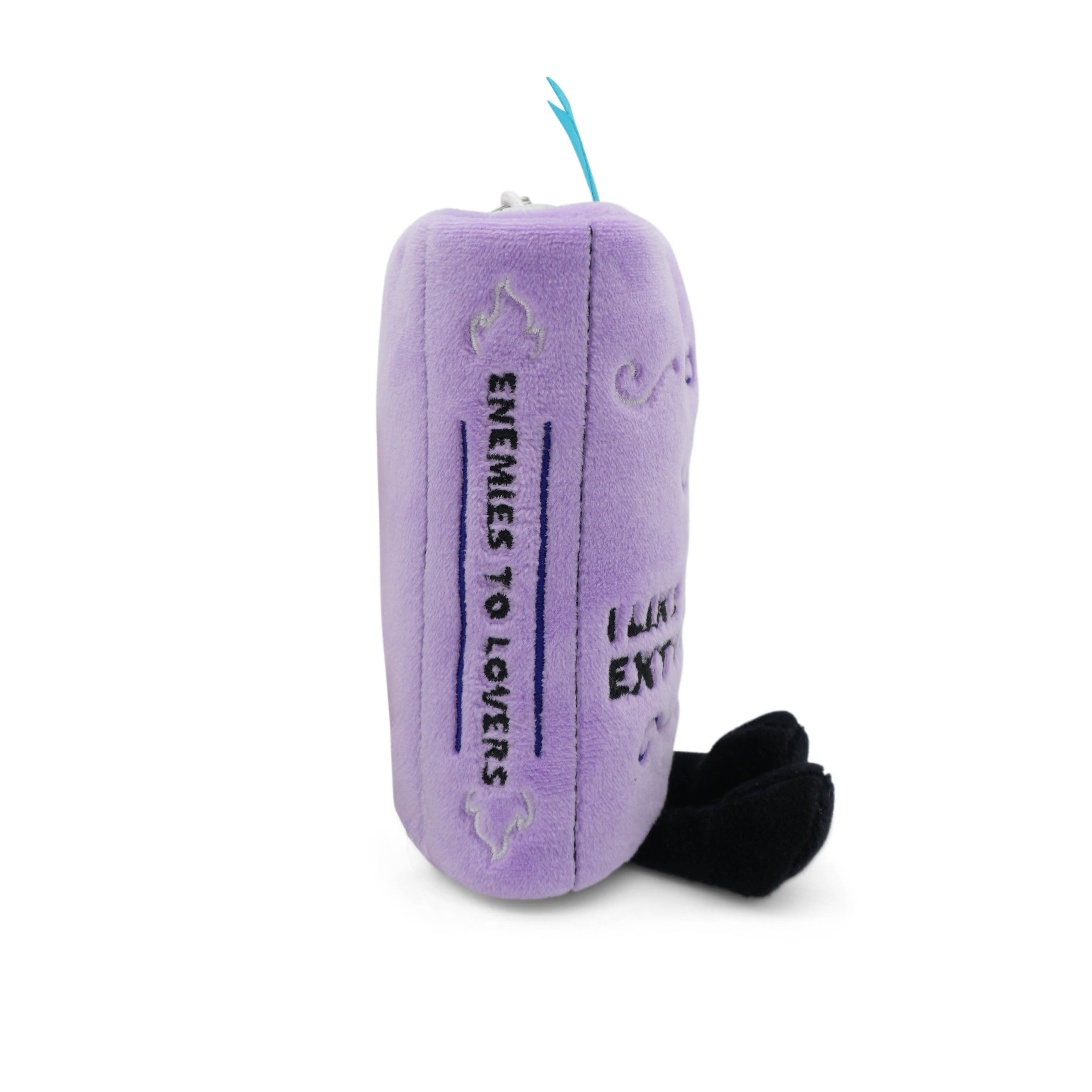 Purple plush book charm with 'enemies to lovers' text written on the spine taken on a white background