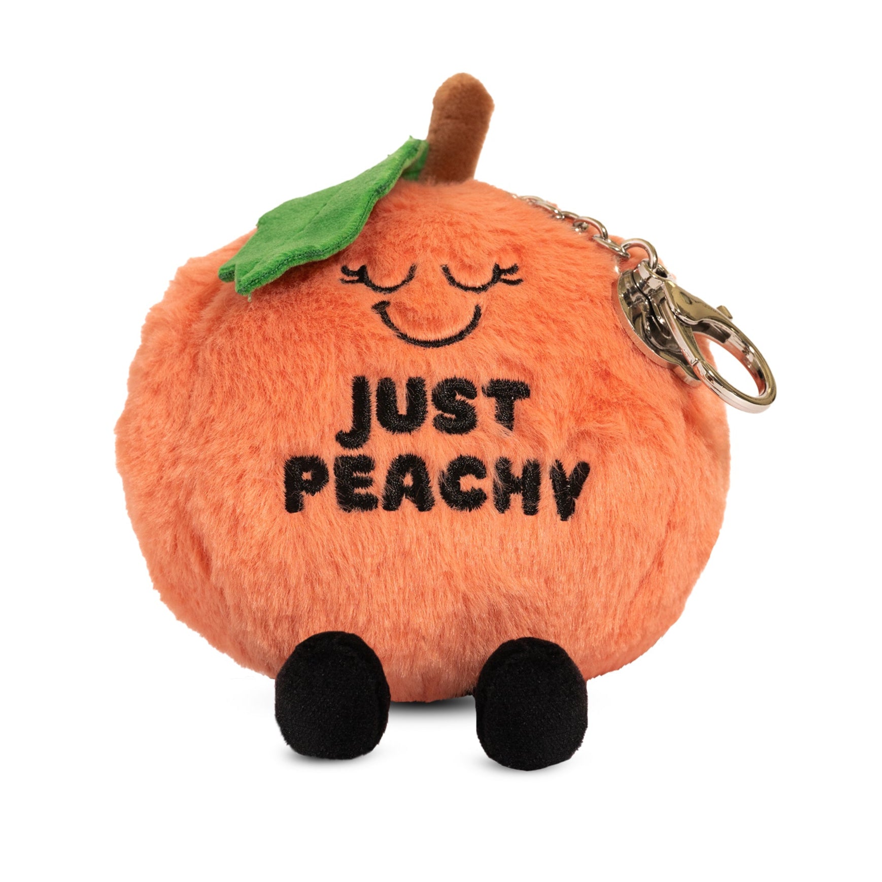 A plush peach bag charm with a smiling face, eyes, dangly legs, and the text 'JUST PEACHY' printed on it. 