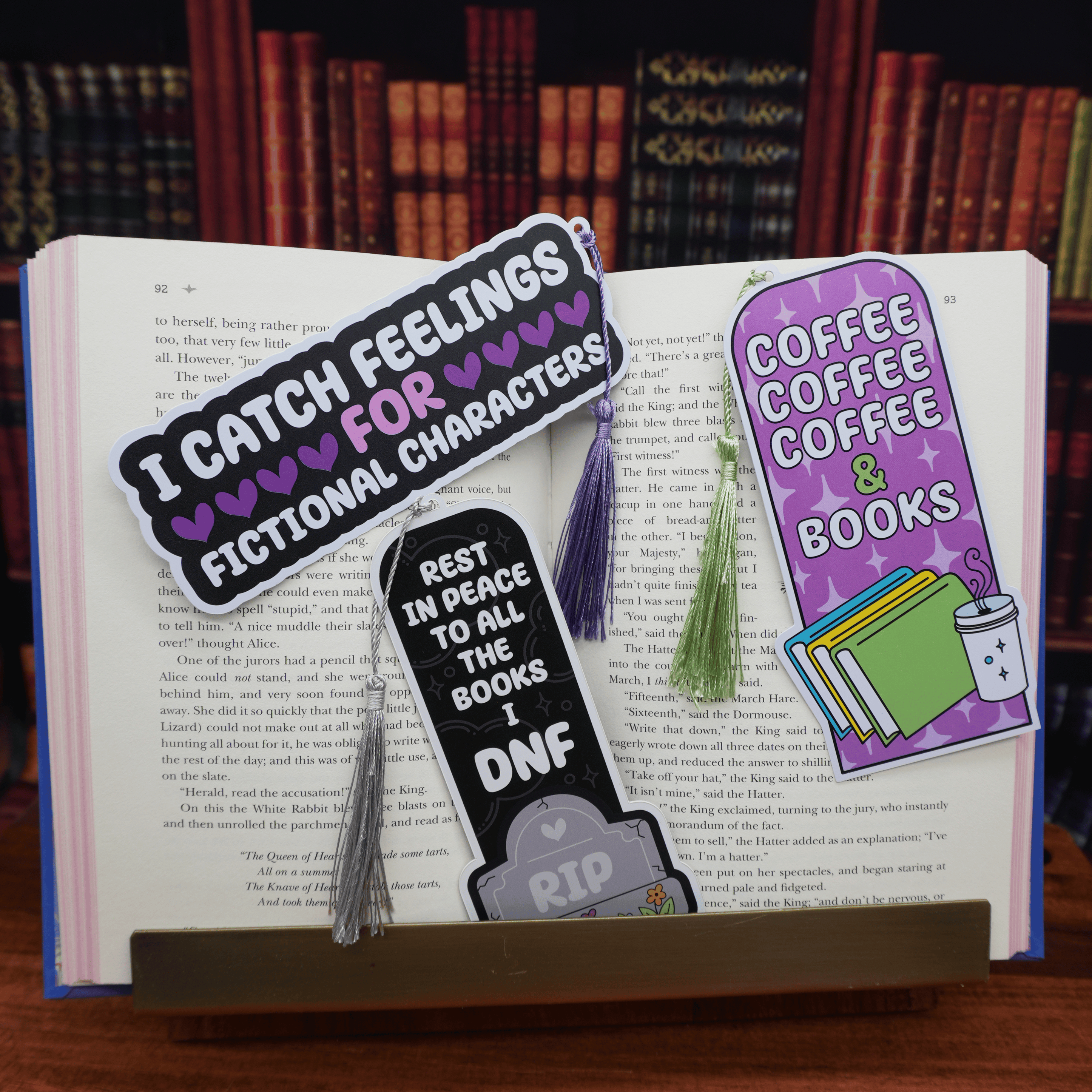 Three bookmarks on an open book with a bookshelf background