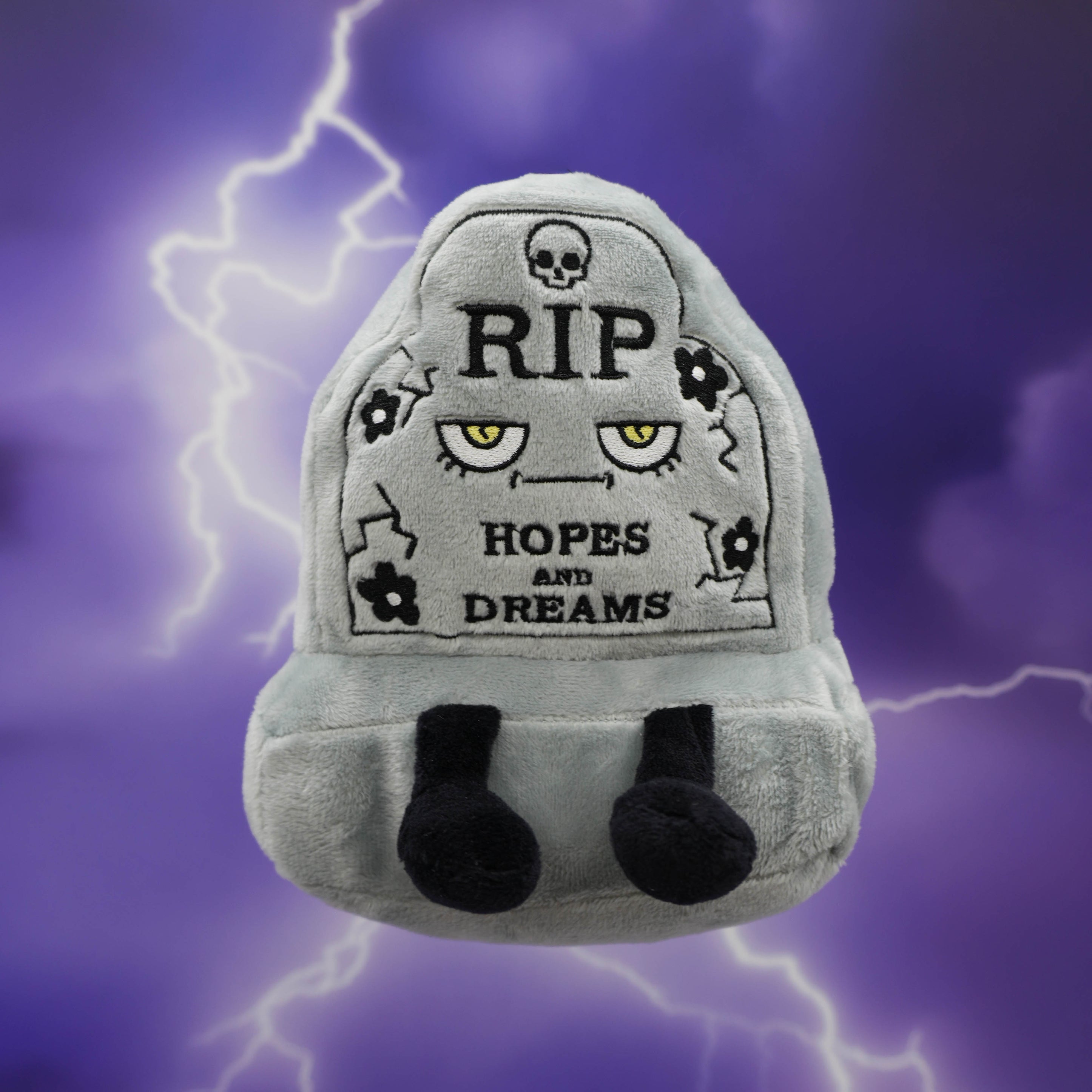 Gray plush toy resembling a headstone with "RIP Hopes and Dream"  text on a purple background with lightning effects.