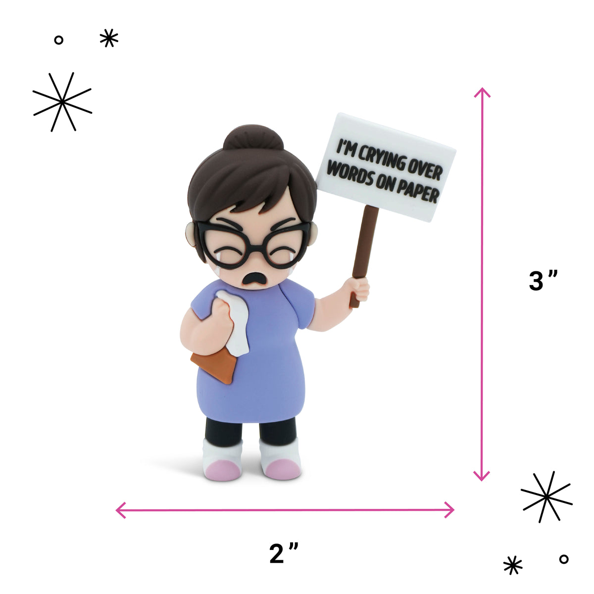 A small figurine of an angry woman with glasses holding a sign that reads 'I'M CRYING OVER WORDS ON PAPER', shown with pink dimension arrows labeled 2 inches wide and 3 inches tall on a white background.