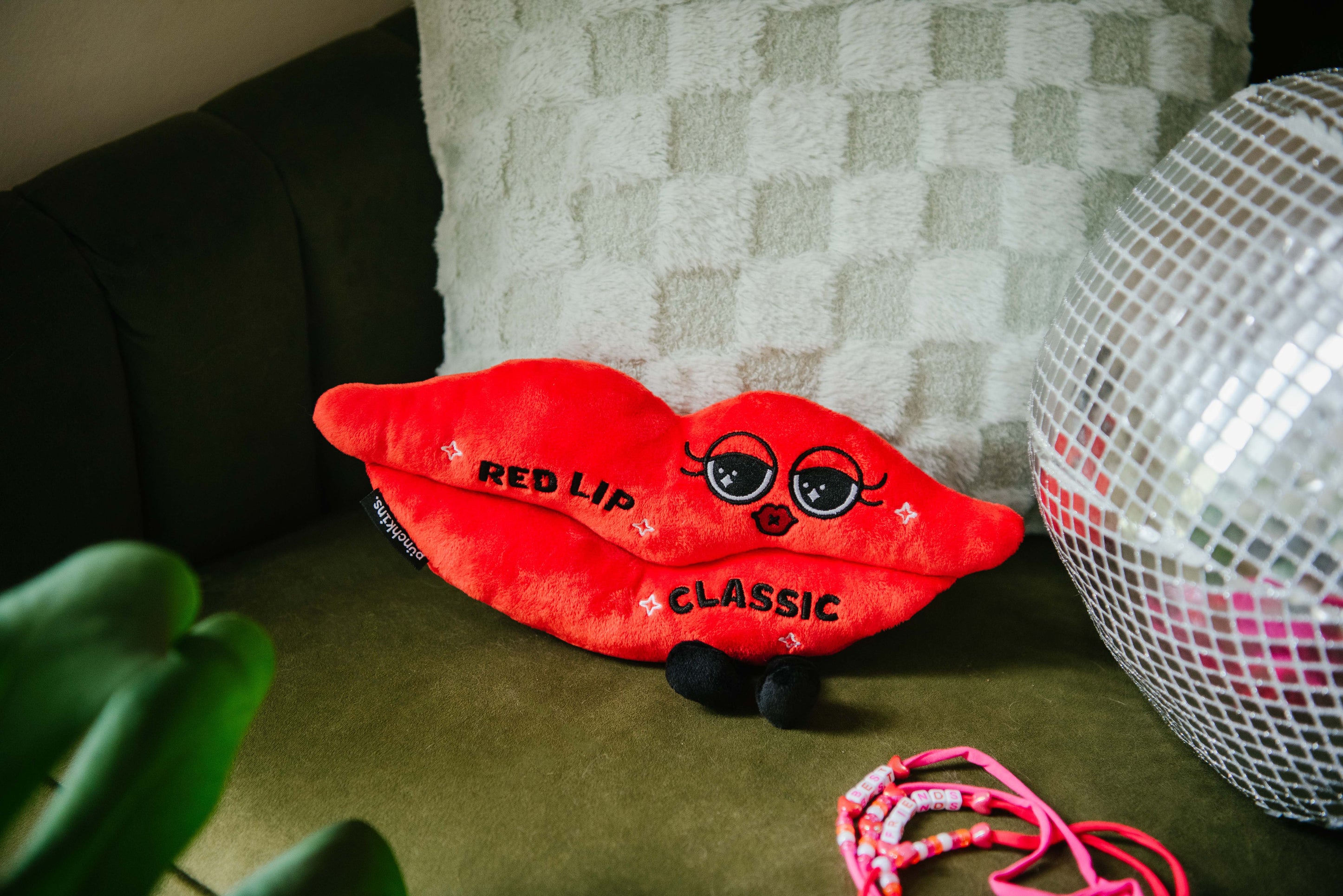 A plush designed to look like a red lip with "Red lip classic" written on it placed on a couch.