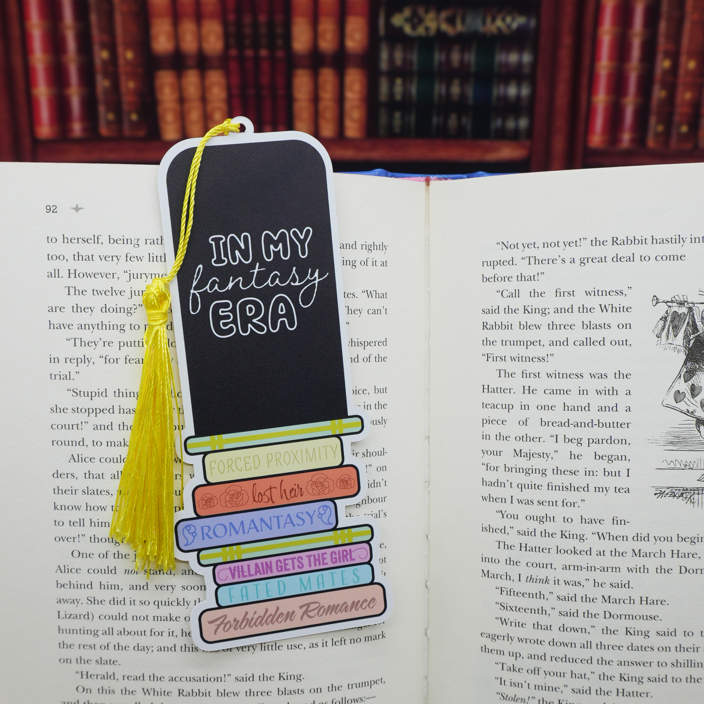 Bookmark with romantasy tropes on an open book in a library setting